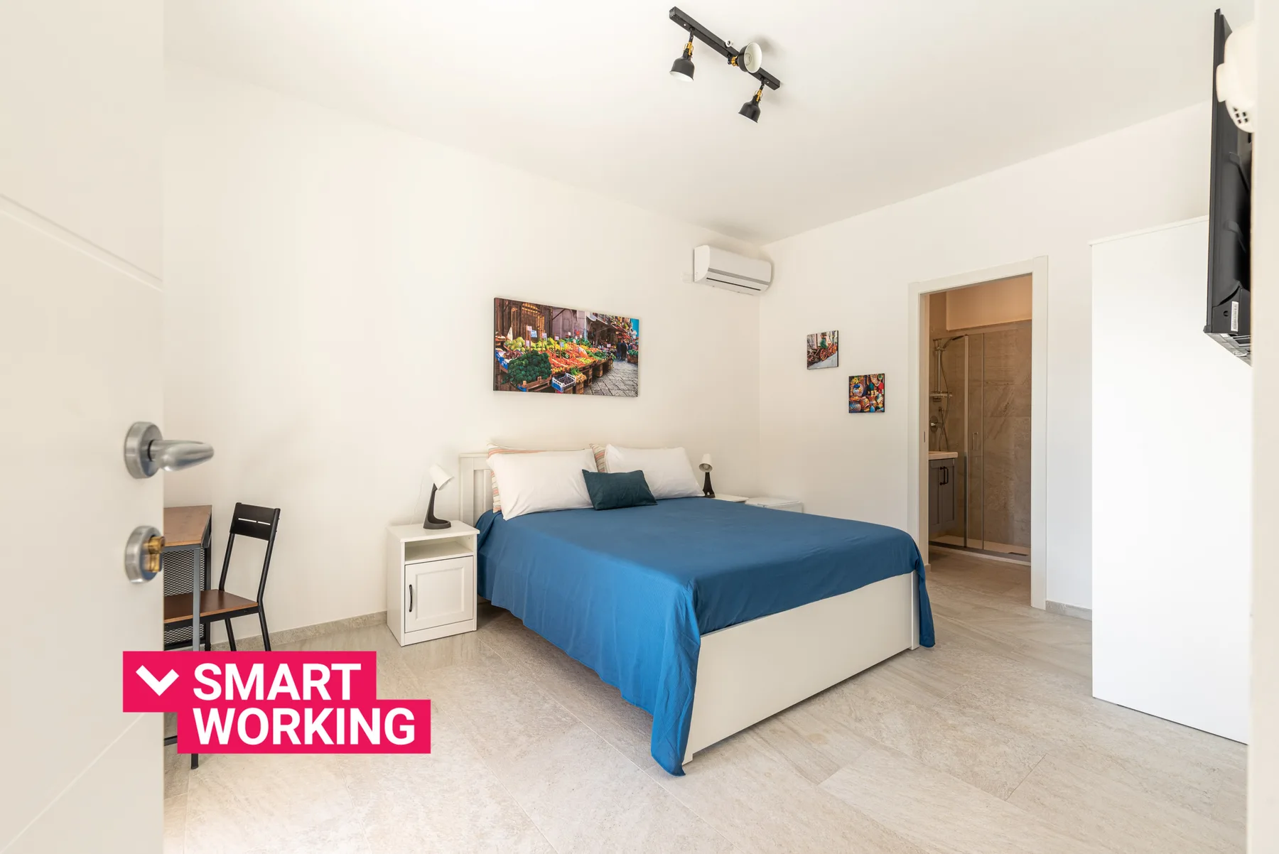 Un dormitorio con una cama cubierta con ropa de cama azul y un pequeño escritorio.