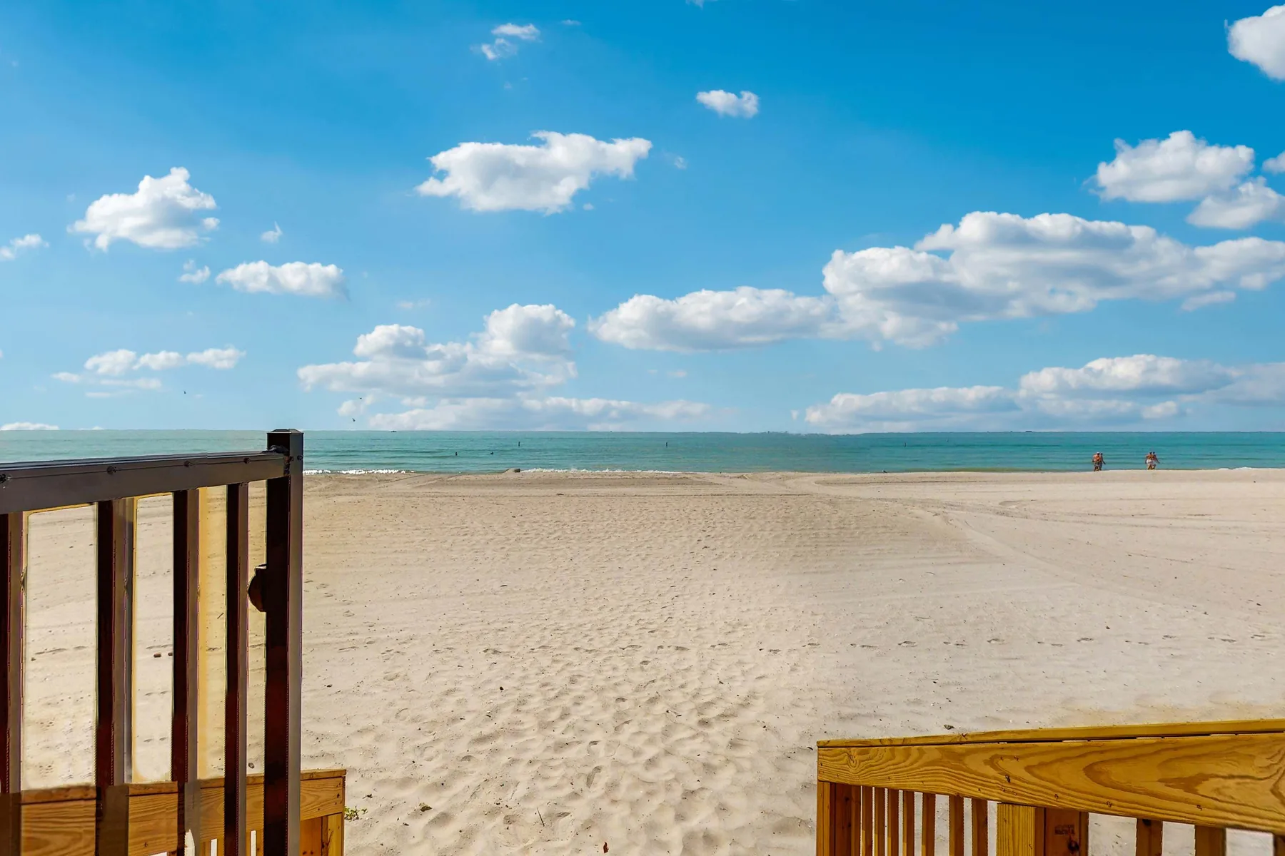 A sandy beach stretches toward the ocean beneath a partly cloudy sky.