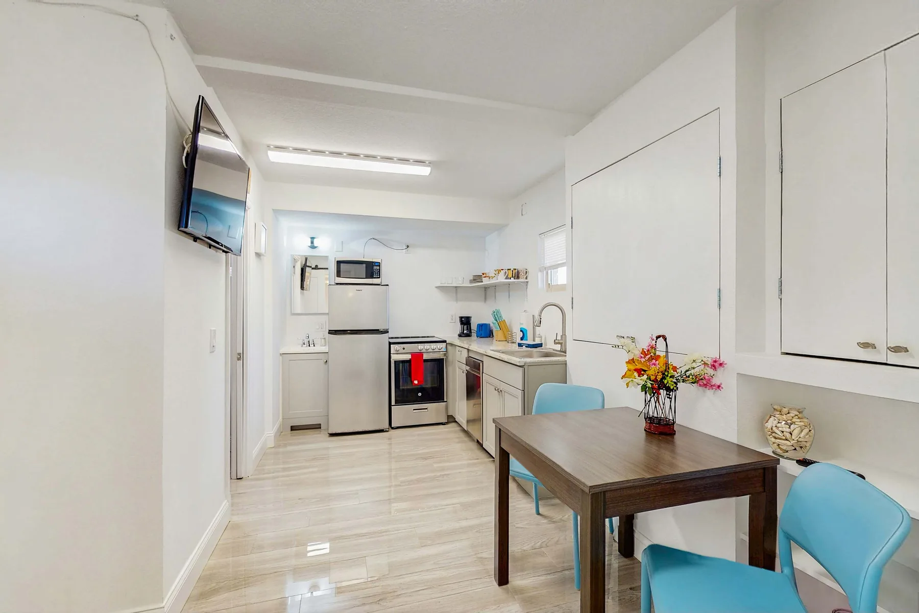 A bright kitchen and dining area with a table, blue seating, and white cabinets.