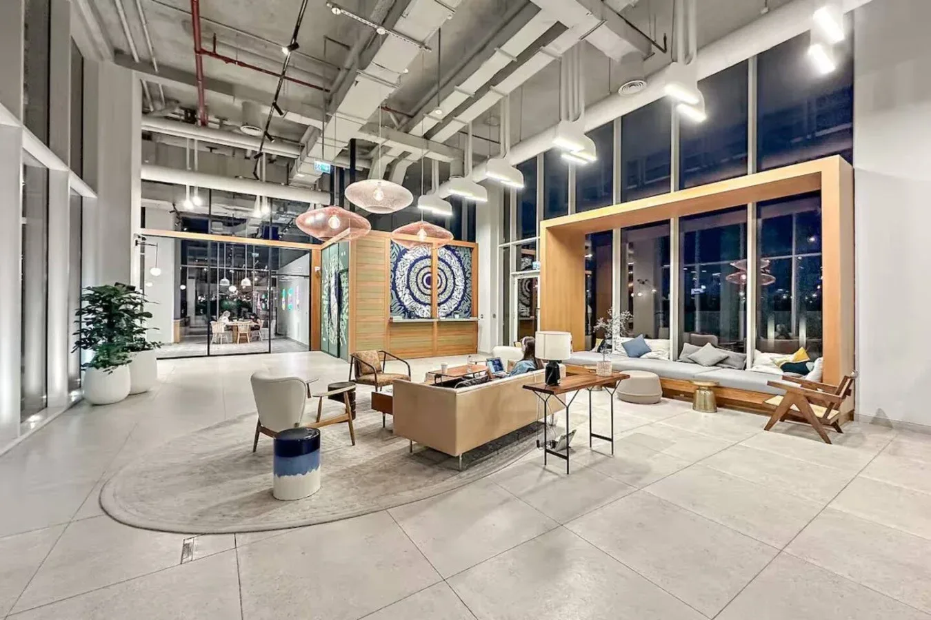 A spacious modern lounge with seating around a low table and tall windows.