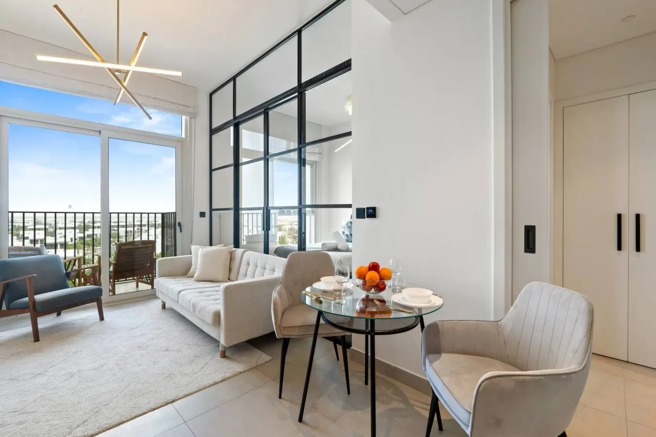 Bright modern living room with white seating beside large glass doors.