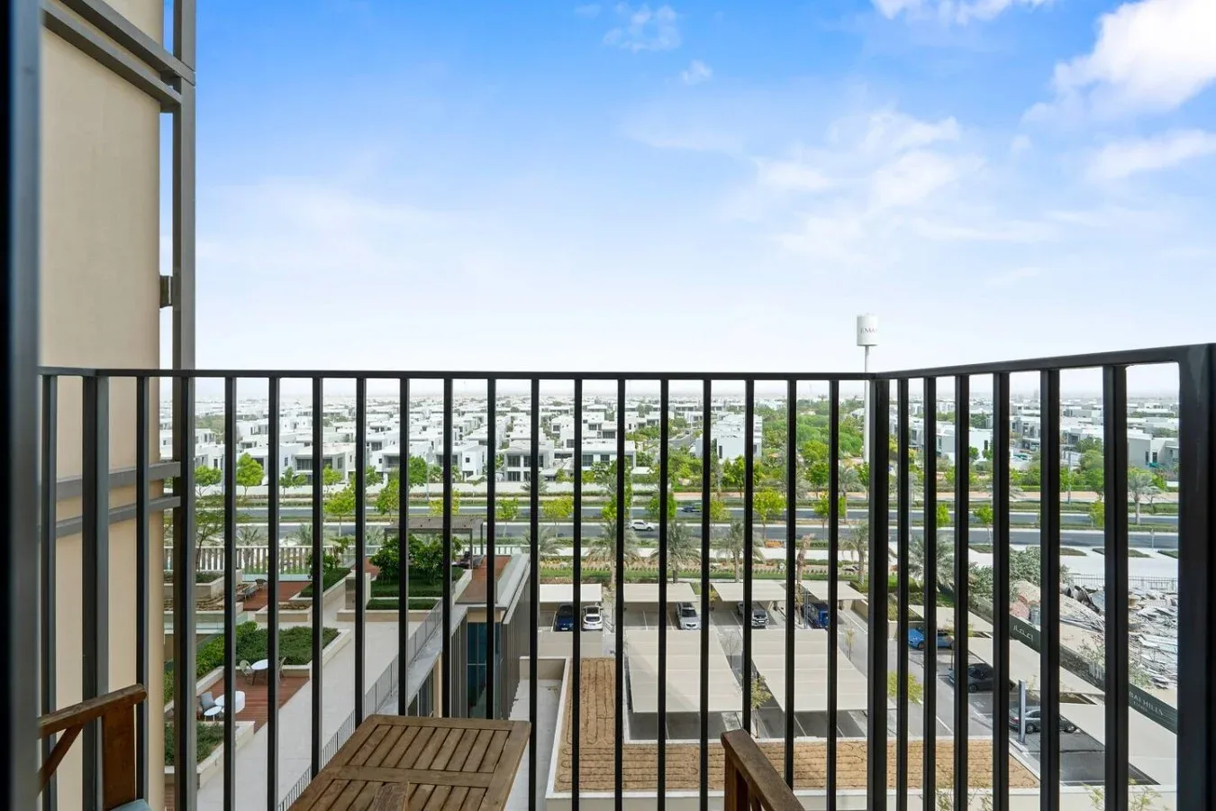 A balcony with dark metal railings overlooks a broad cityscape.