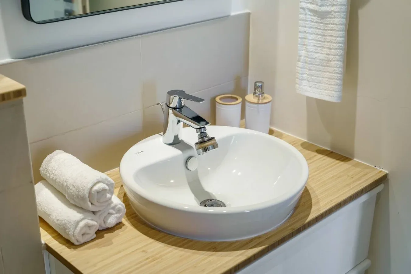 A bathroom vanity with a white basin, chrome faucet, and folded towels.