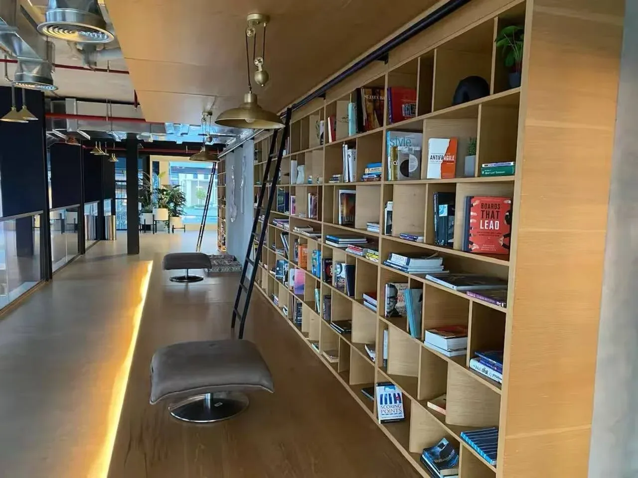 A lounge area with a long bookshelf and upholstered seating.
