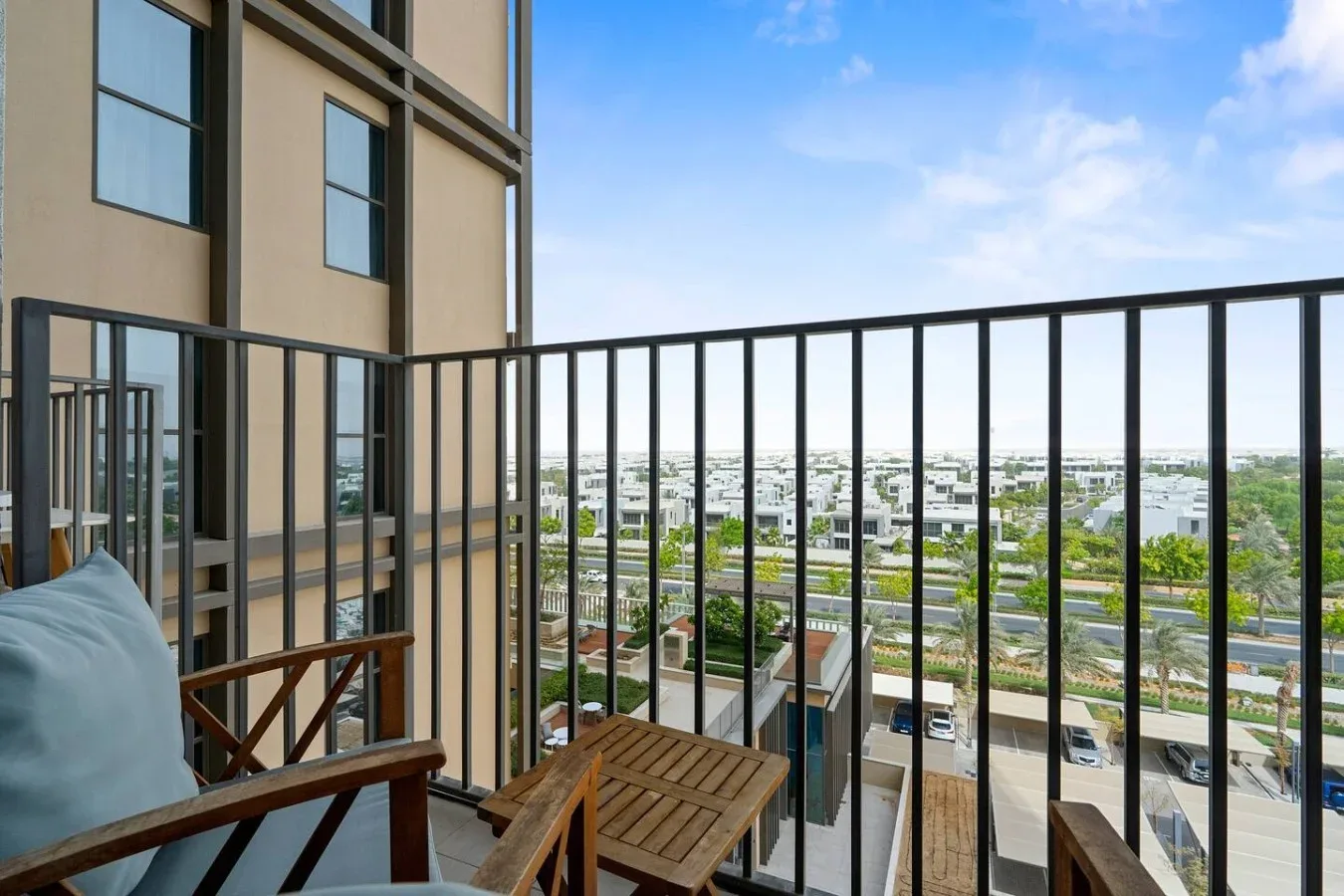 A balcony seating area overlooks a neighborhood beneath a clear blue sky.