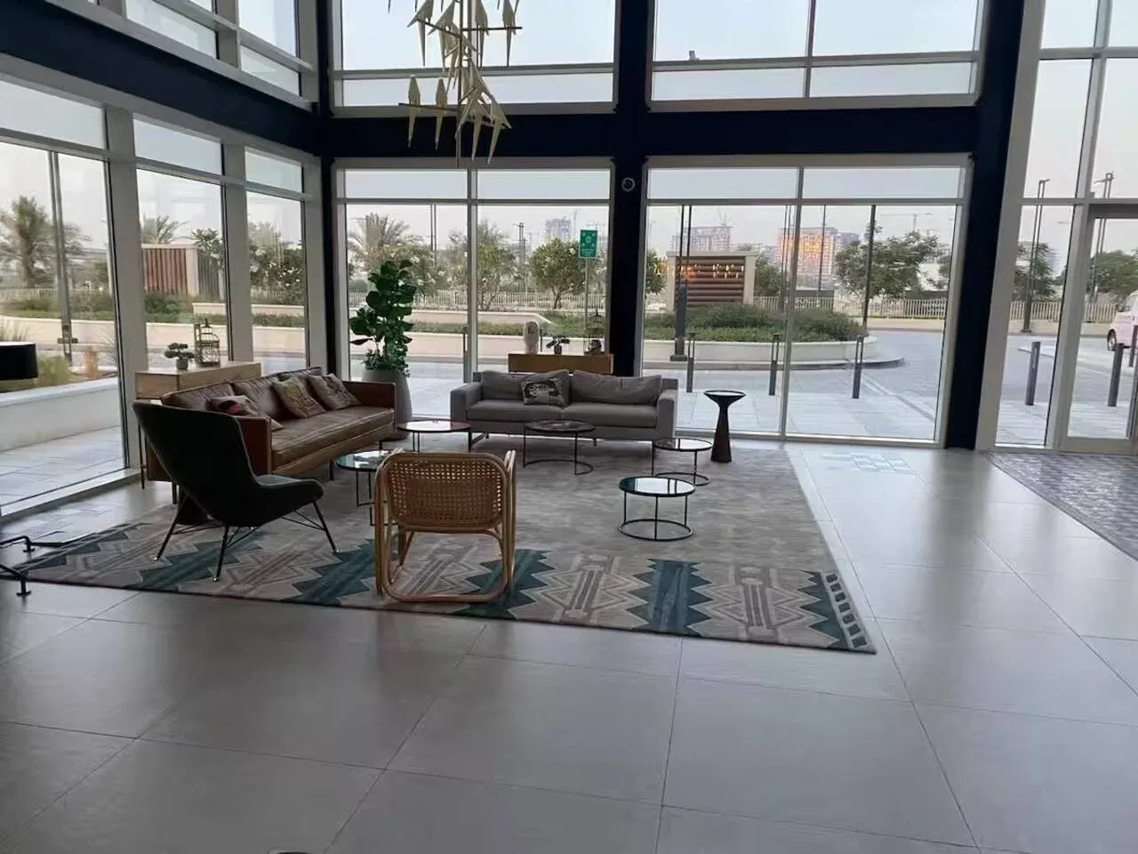A modern lounge with seating arranged on a patterned rug beside large windows.