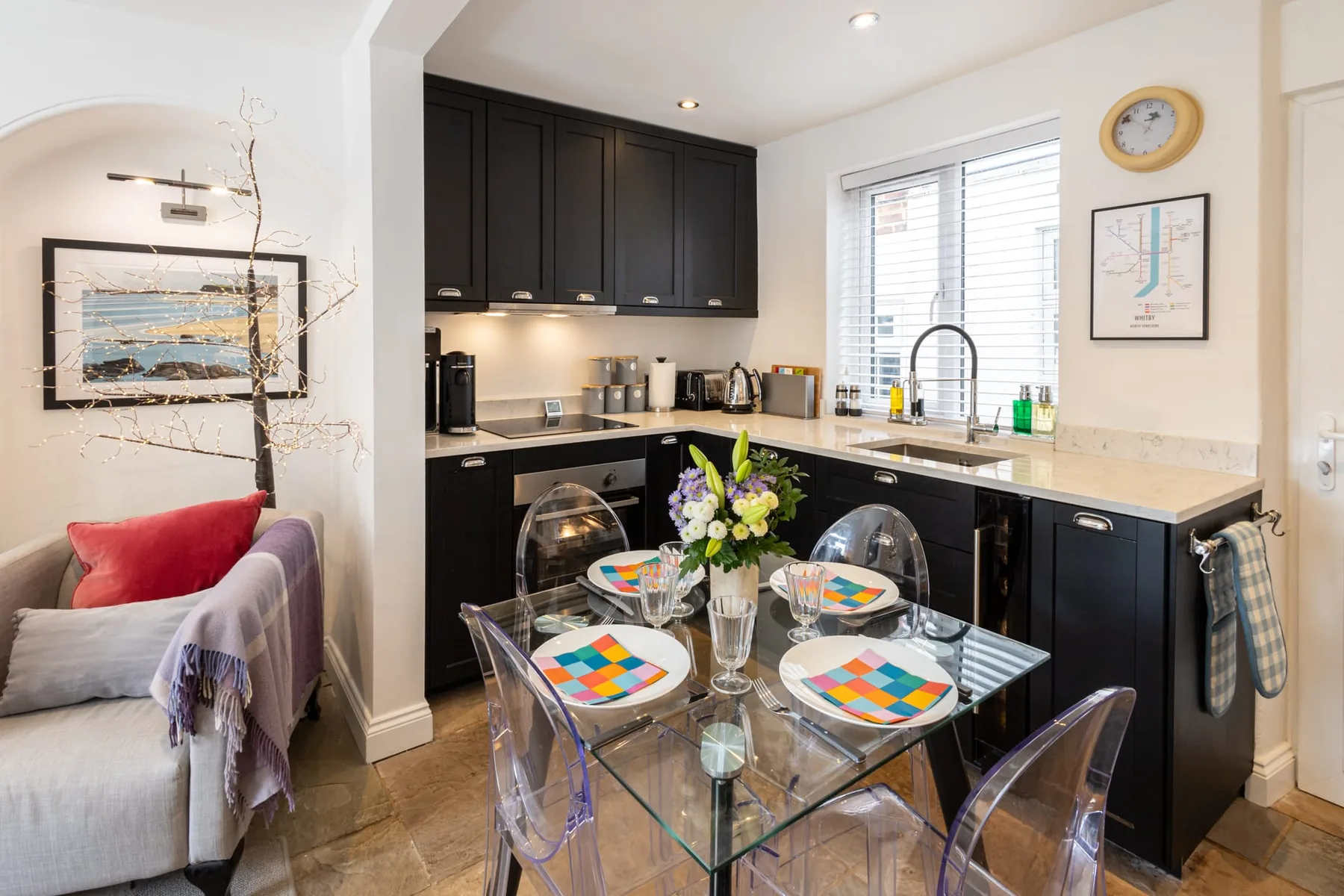A compact kitchen and dining area with dark cabinets and a glass table.