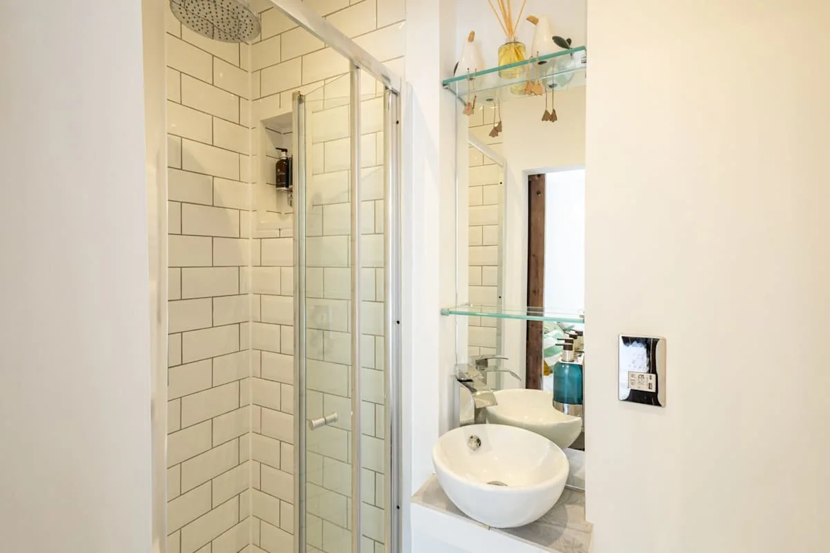 A tiled bathroom with a glass shower and a vessel sink.