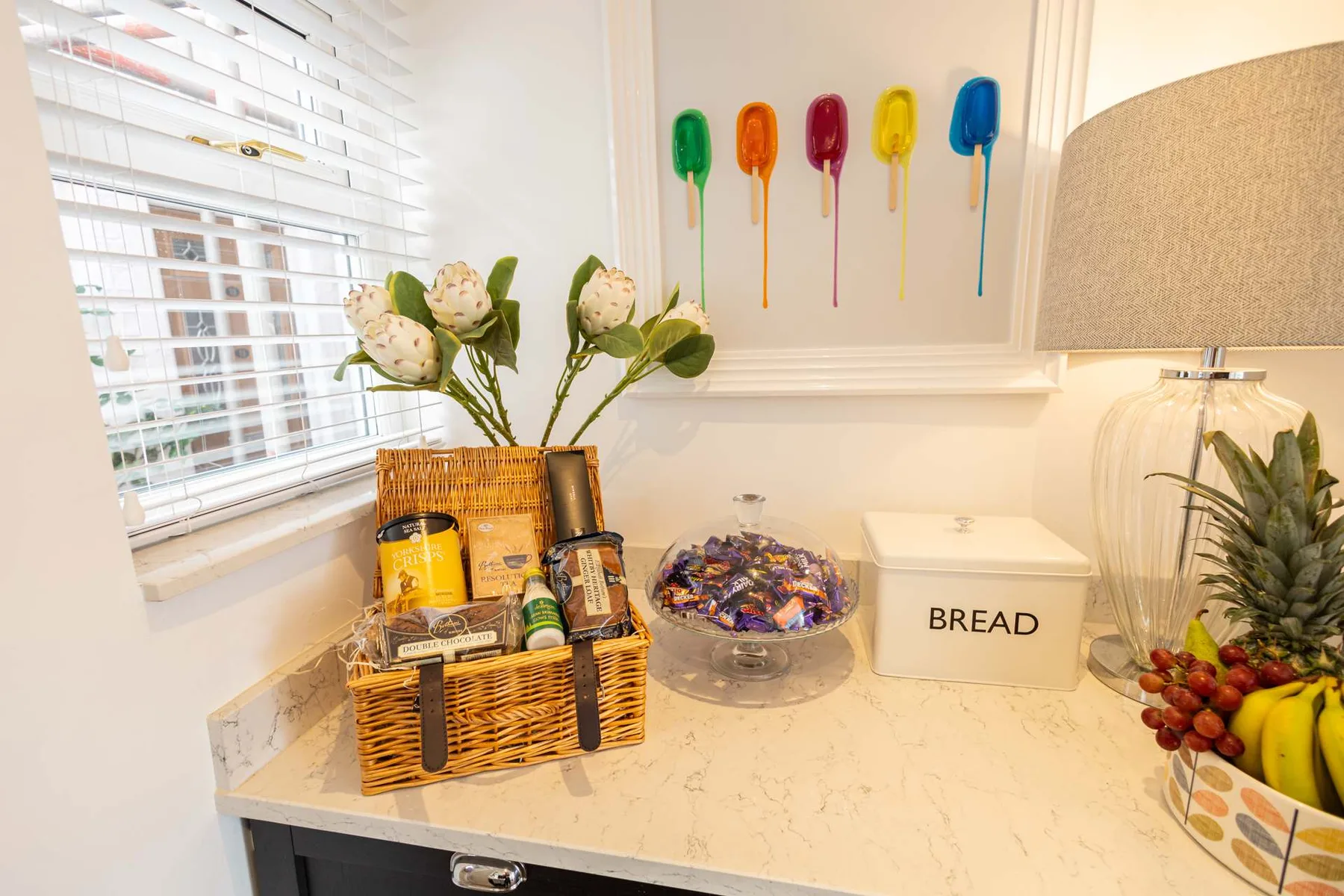 A countertop snack station with a wicker basket and a bowl of wrapped treats.