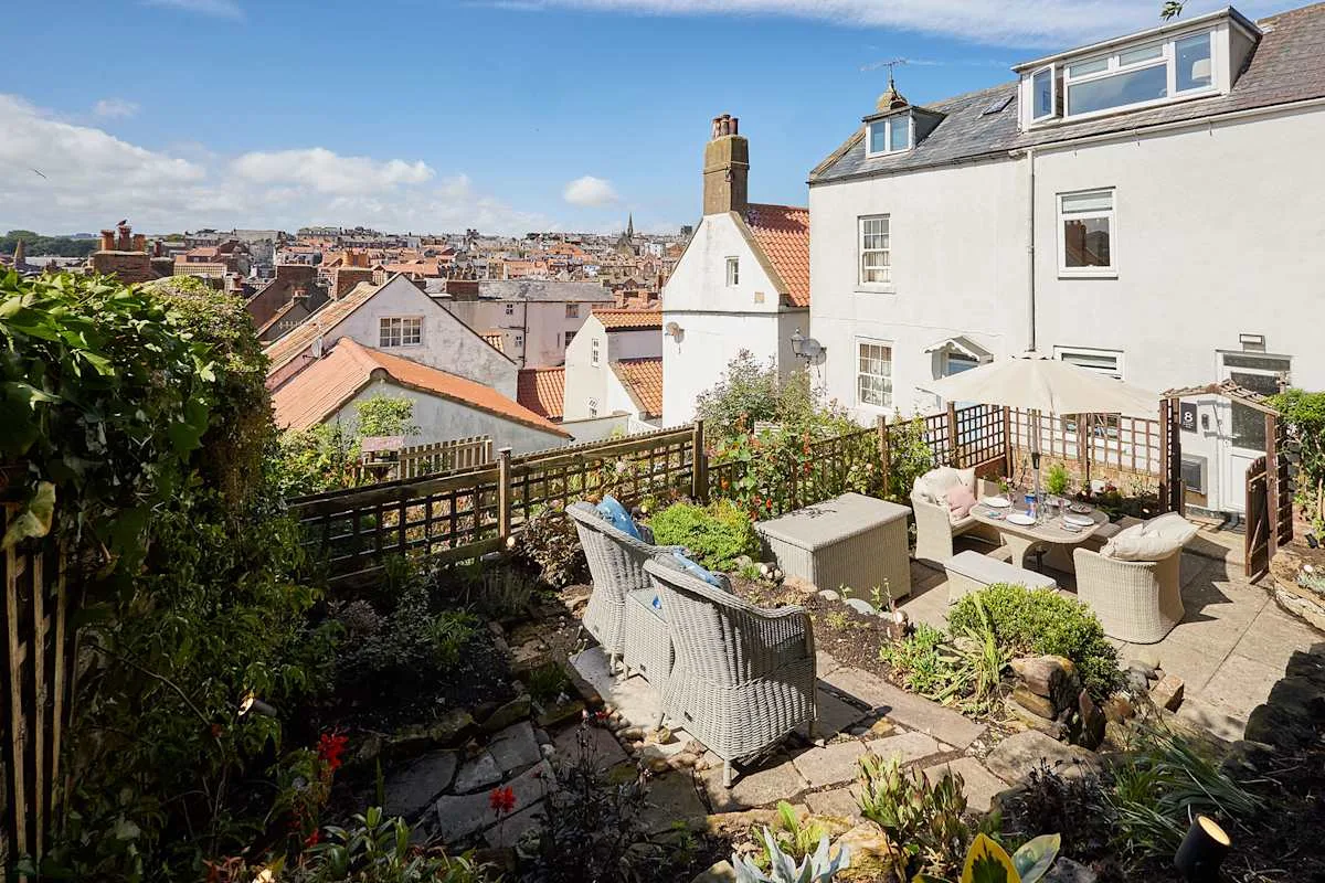 A furnished outdoor terrace overlooks a dense neighborhood of rooftops.