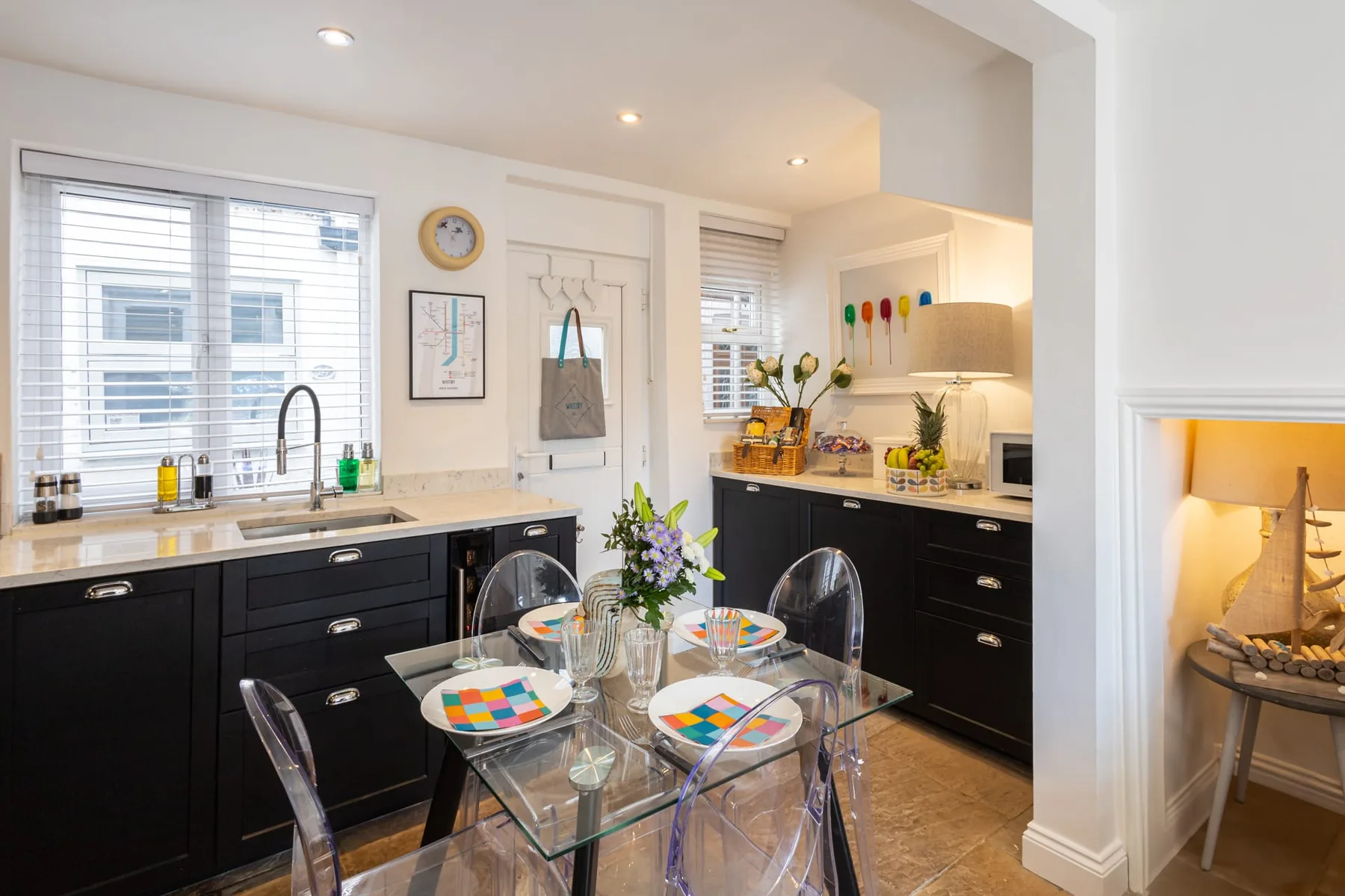 A bright kitchen and dining area with dark cabinets and a glass dining table.