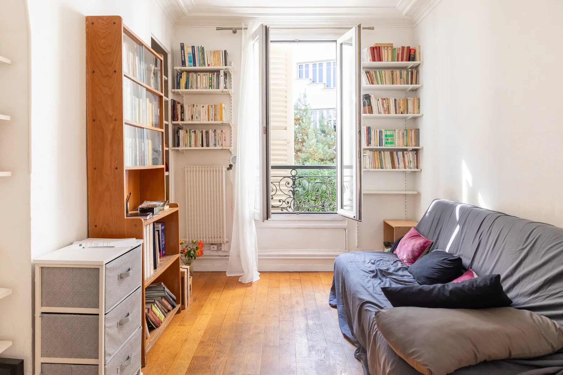 Una sala luminosa con asientos y estanterías junto a una ventana abierta.
