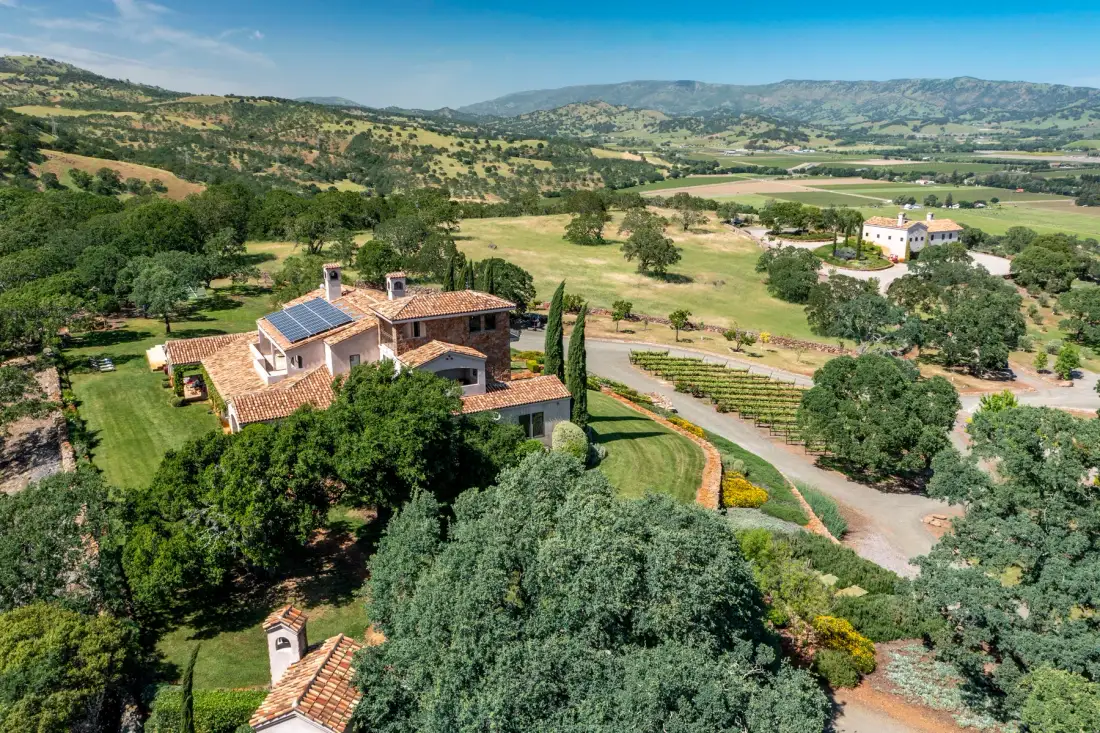 Aerial view of a countryside property among trees and rolling hills.