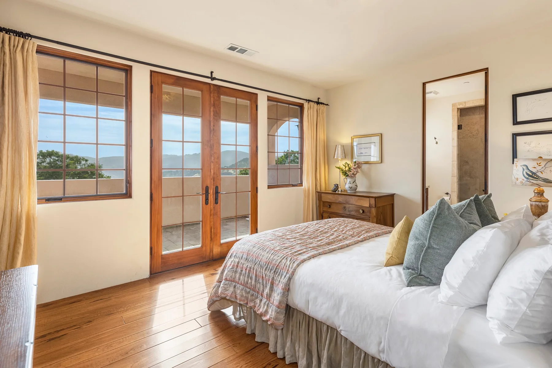 Bedroom with a bed beside wood-framed glass doors and windows.