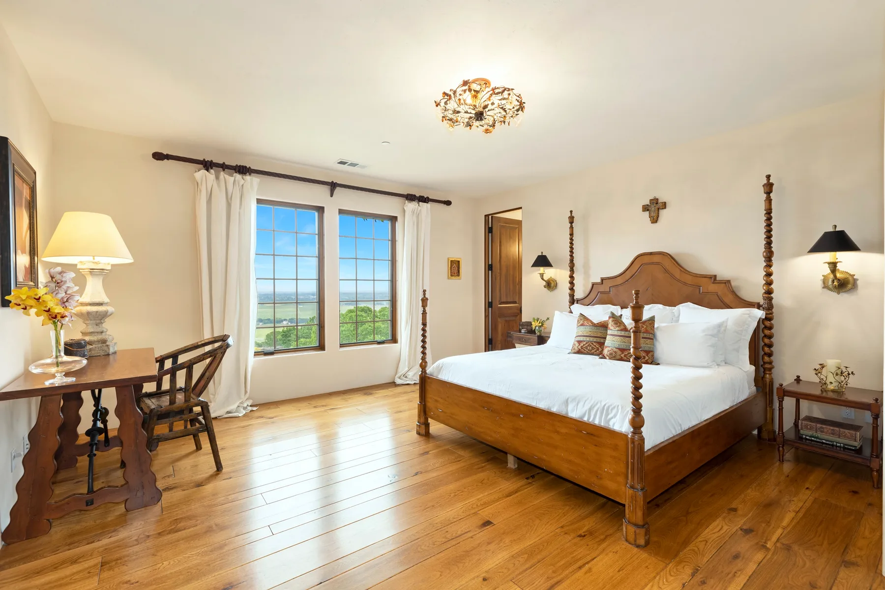 A bedroom with a wooden four-poster bed and tall windows.