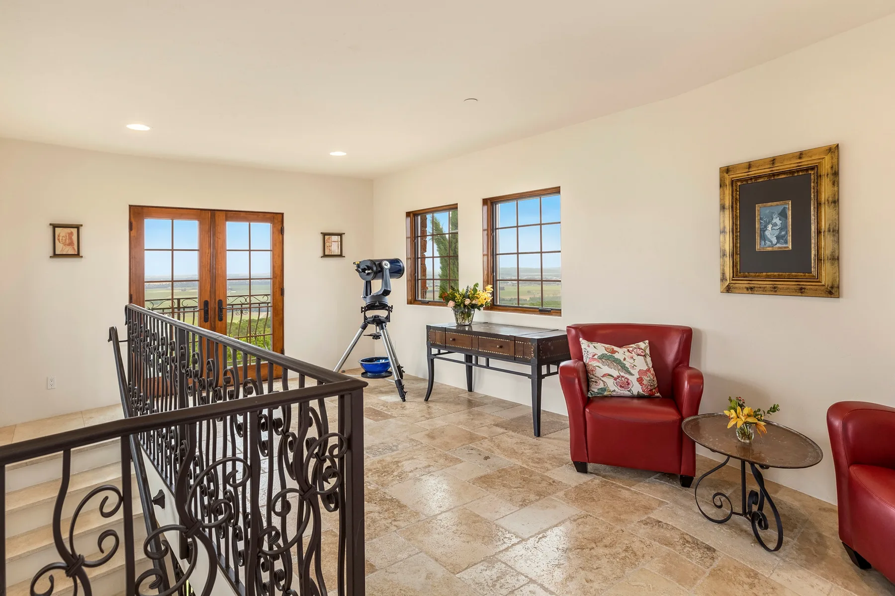A bright sitting area with red seating, tall windows, and a decorative railing.