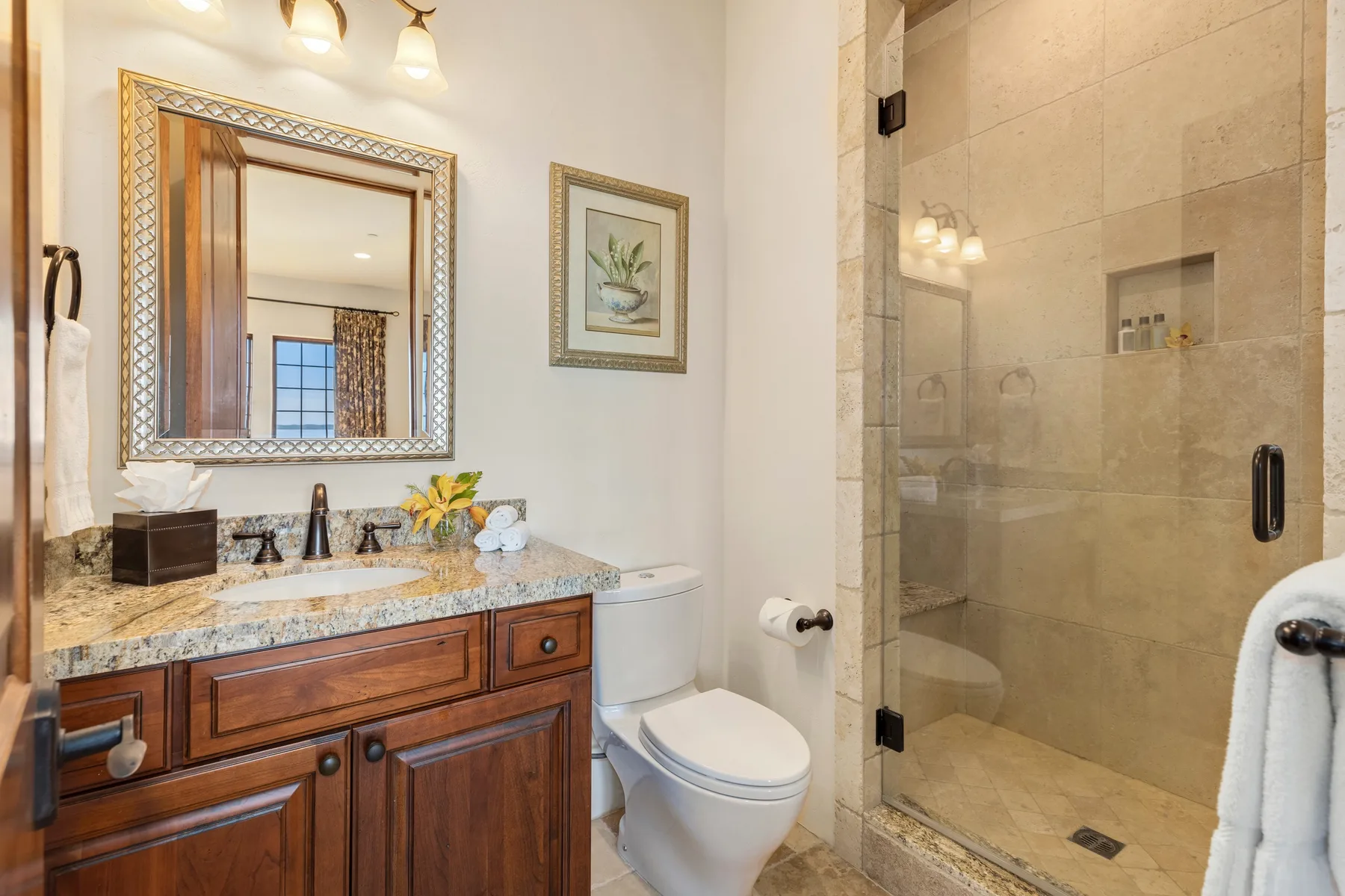 A bathroom with a wood vanity, toilet, and glass shower.