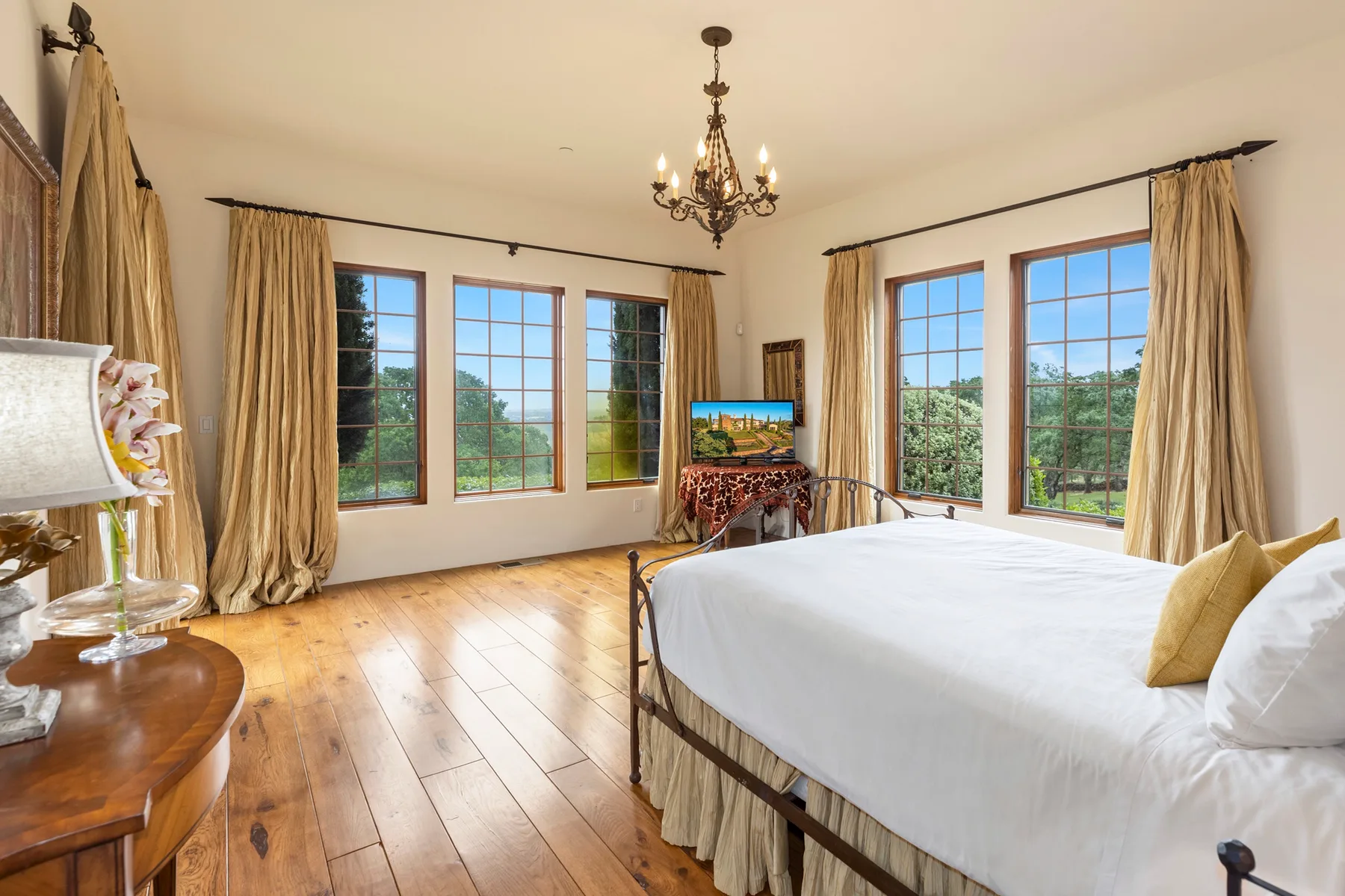 A bright bedroom with a large bed and windows overlooking greenery.