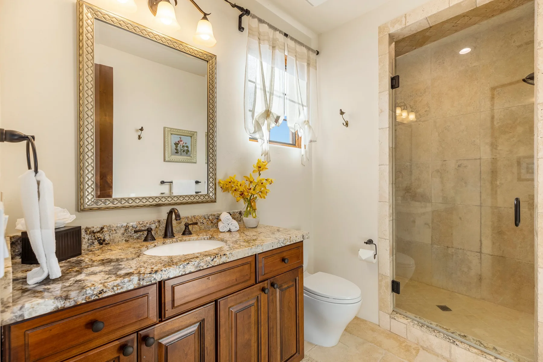 A bathroom vanity with a large mirror stands beside a glass shower.