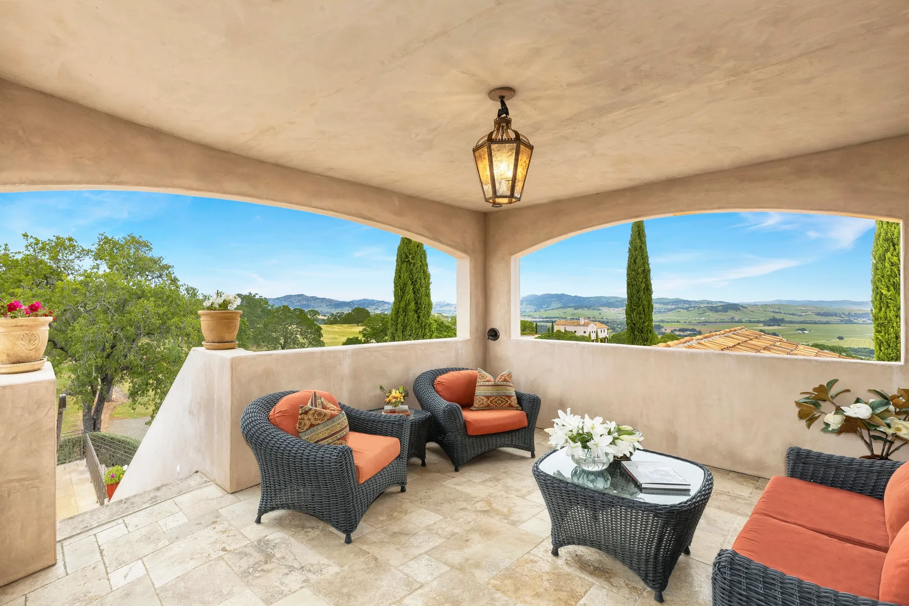 A covered terrace with wicker seating and a view of the surrounding countryside.