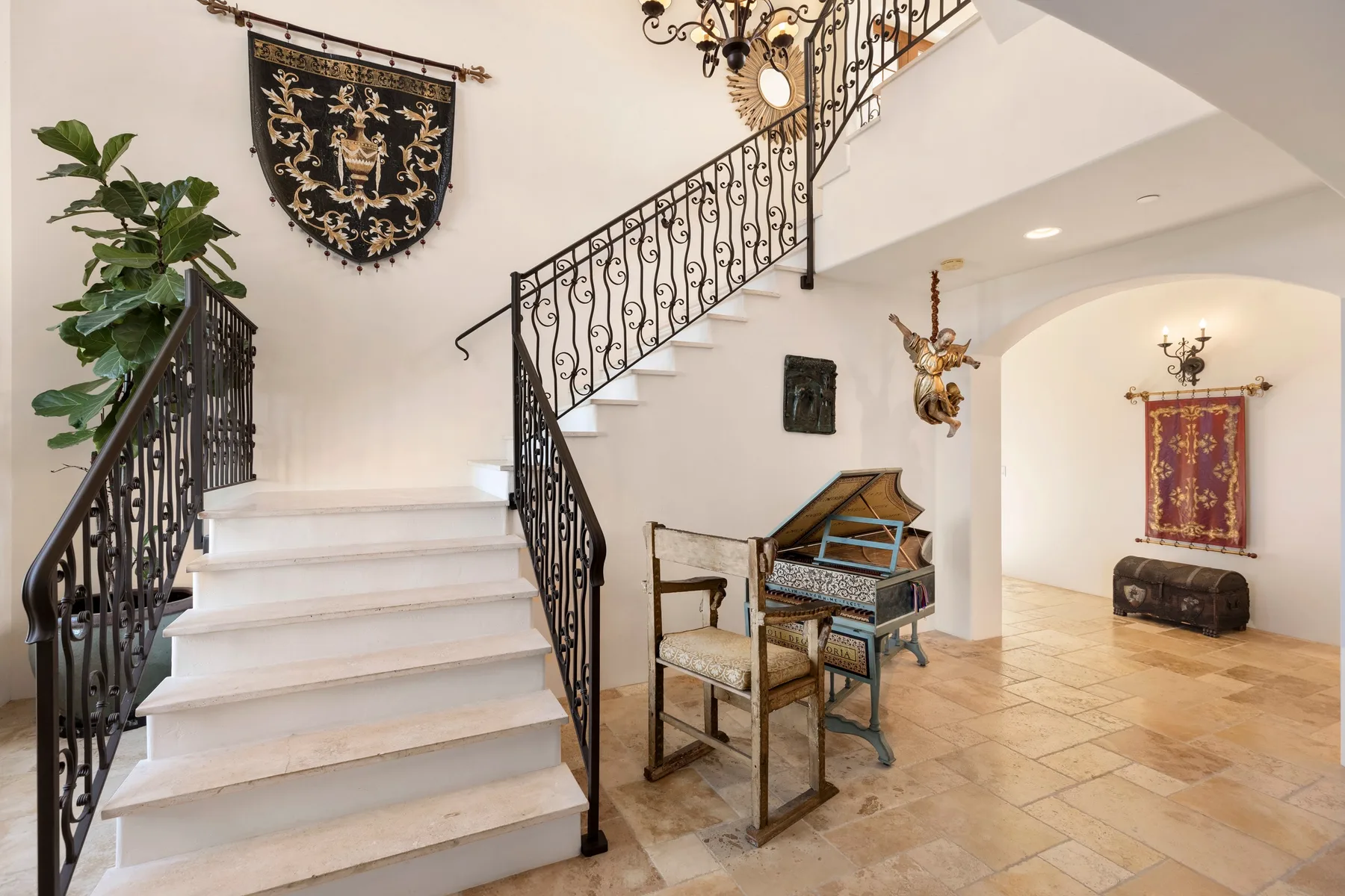 An interior staircase with ornate railings rises above a tiled foyer.