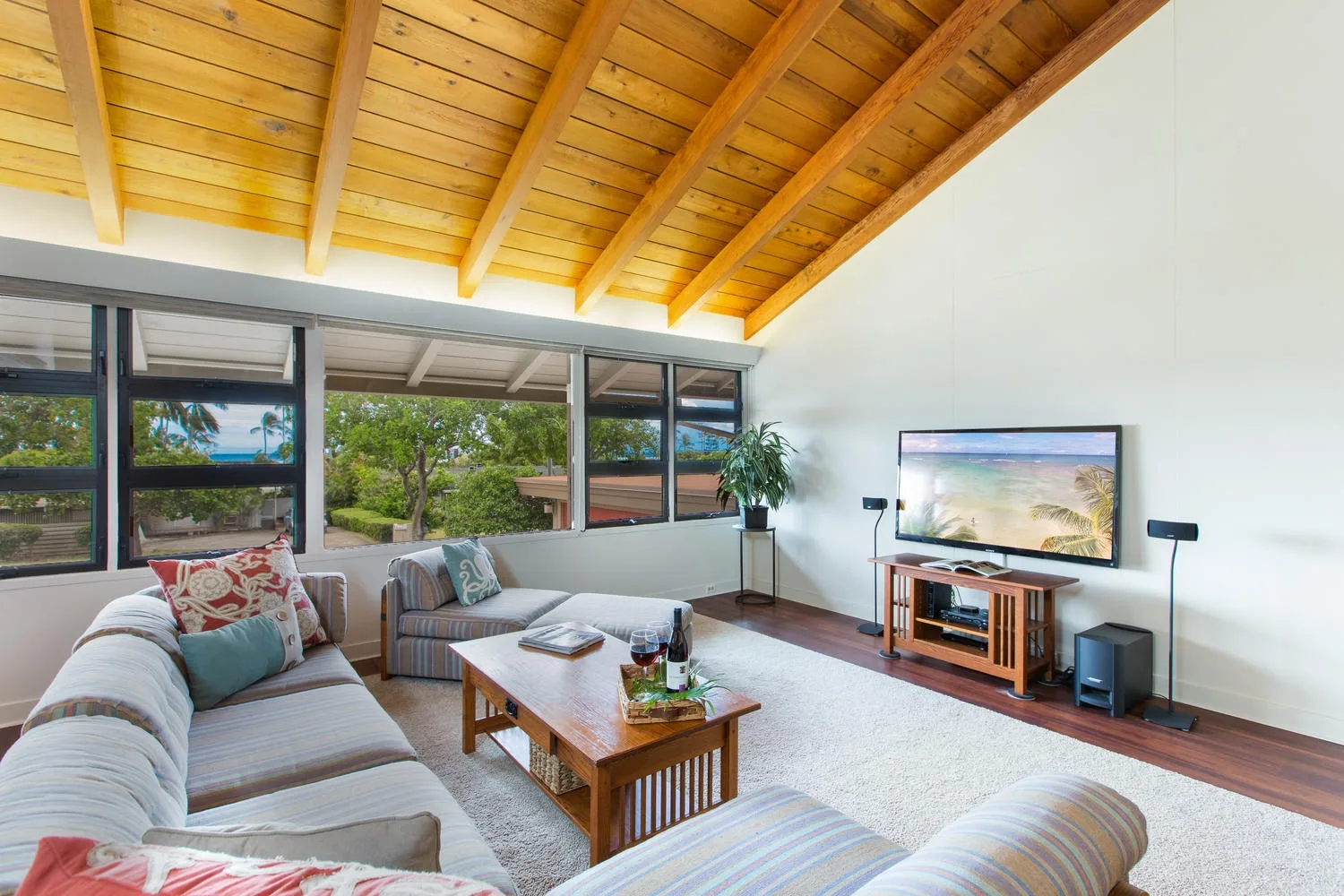 Una sala de estar luminosa con amplias ventanas, una zona para sentarse y techo de madera.