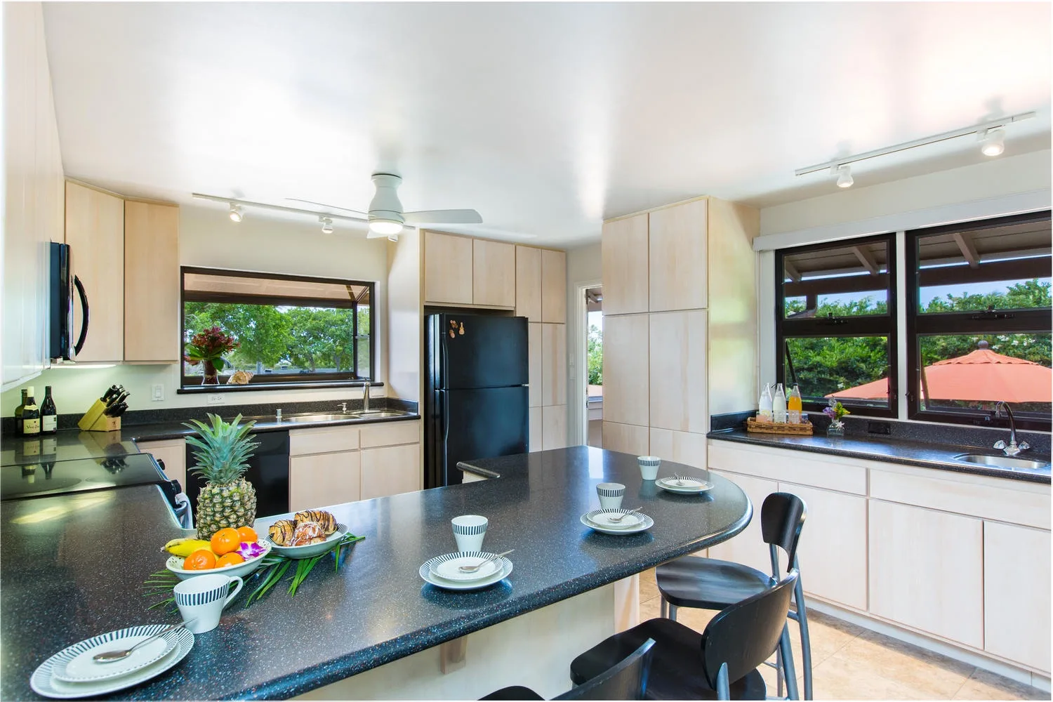 Una cocina luminosa con una amplia encimera oscura y ventanas con vistas a la vegetación.