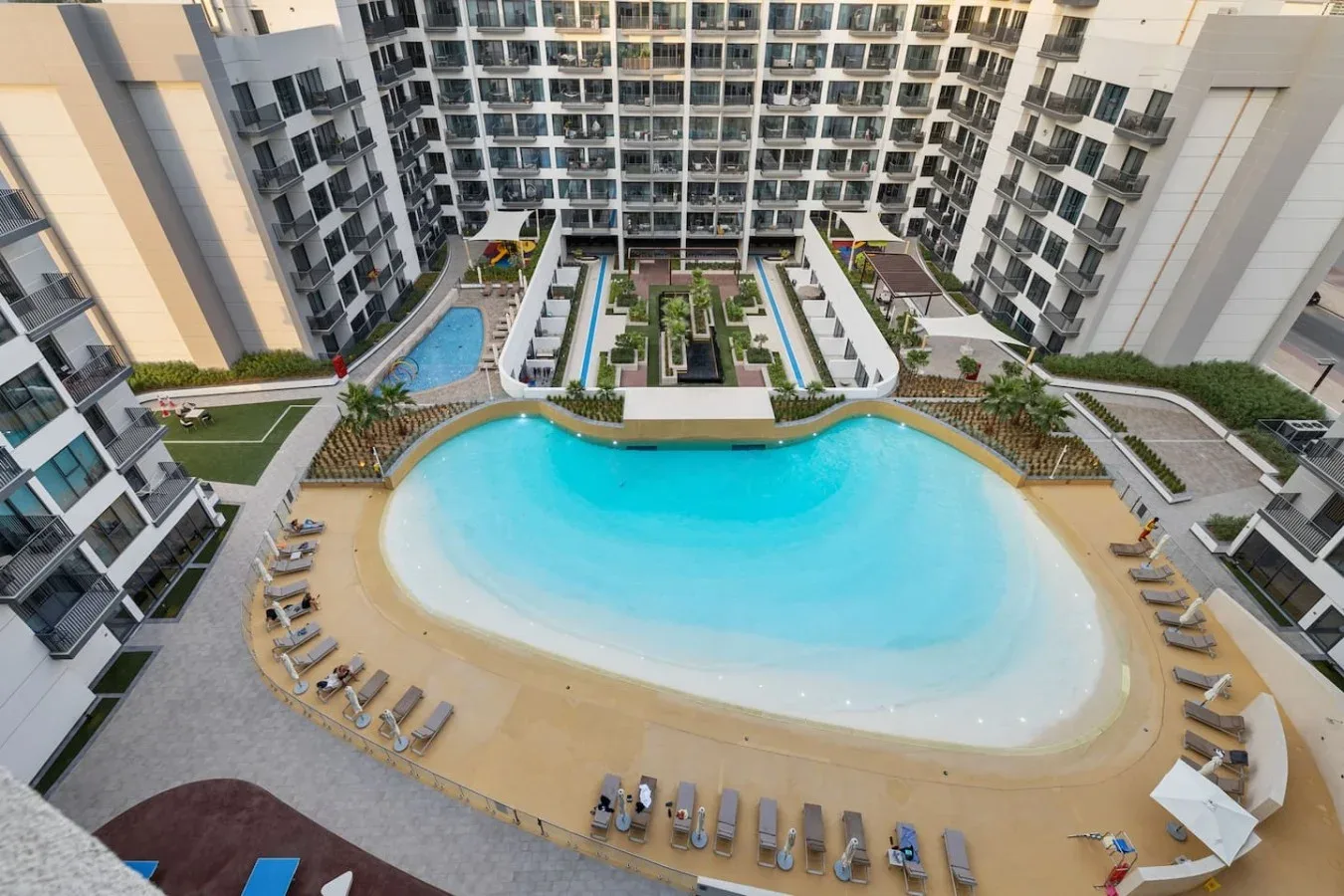 Una gran piscina y asientos de descanso están dentro del patio de un edificio de varios pisos.