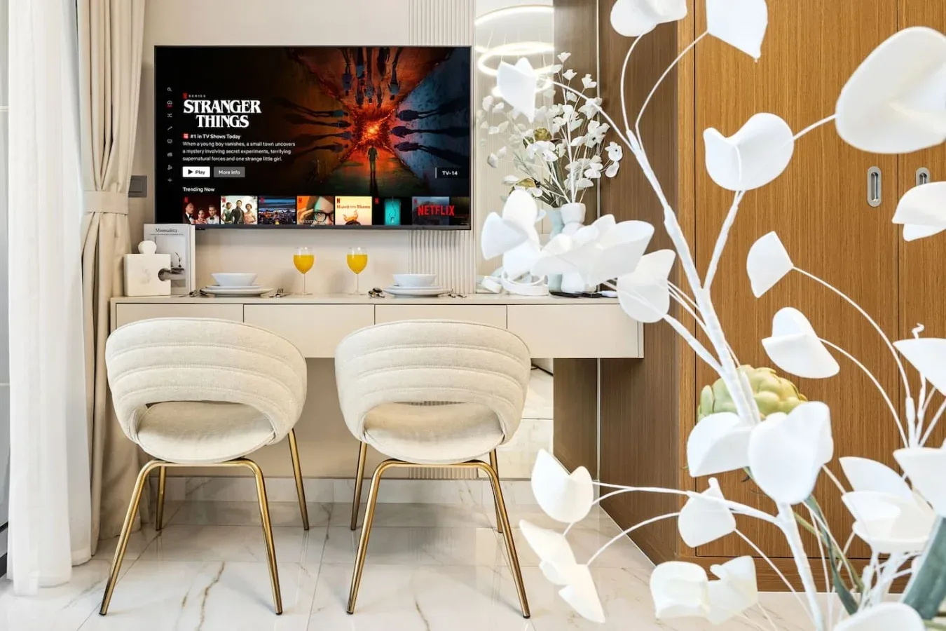 Un comedor con dos asientos tapizados, una mesa y un televisor montado en la pared.