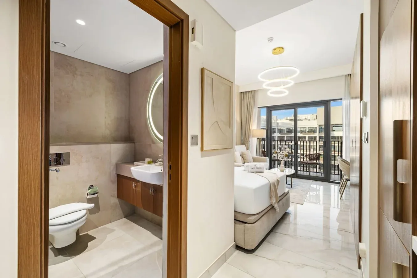 Un dormitorio luminoso da a un balcón, con un baño contiguo visible desde la entrada.