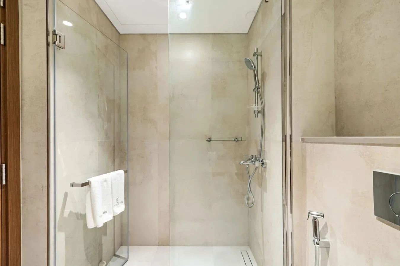 Un baño alicatado con ducha de vidrio y accesorios en la pared.
