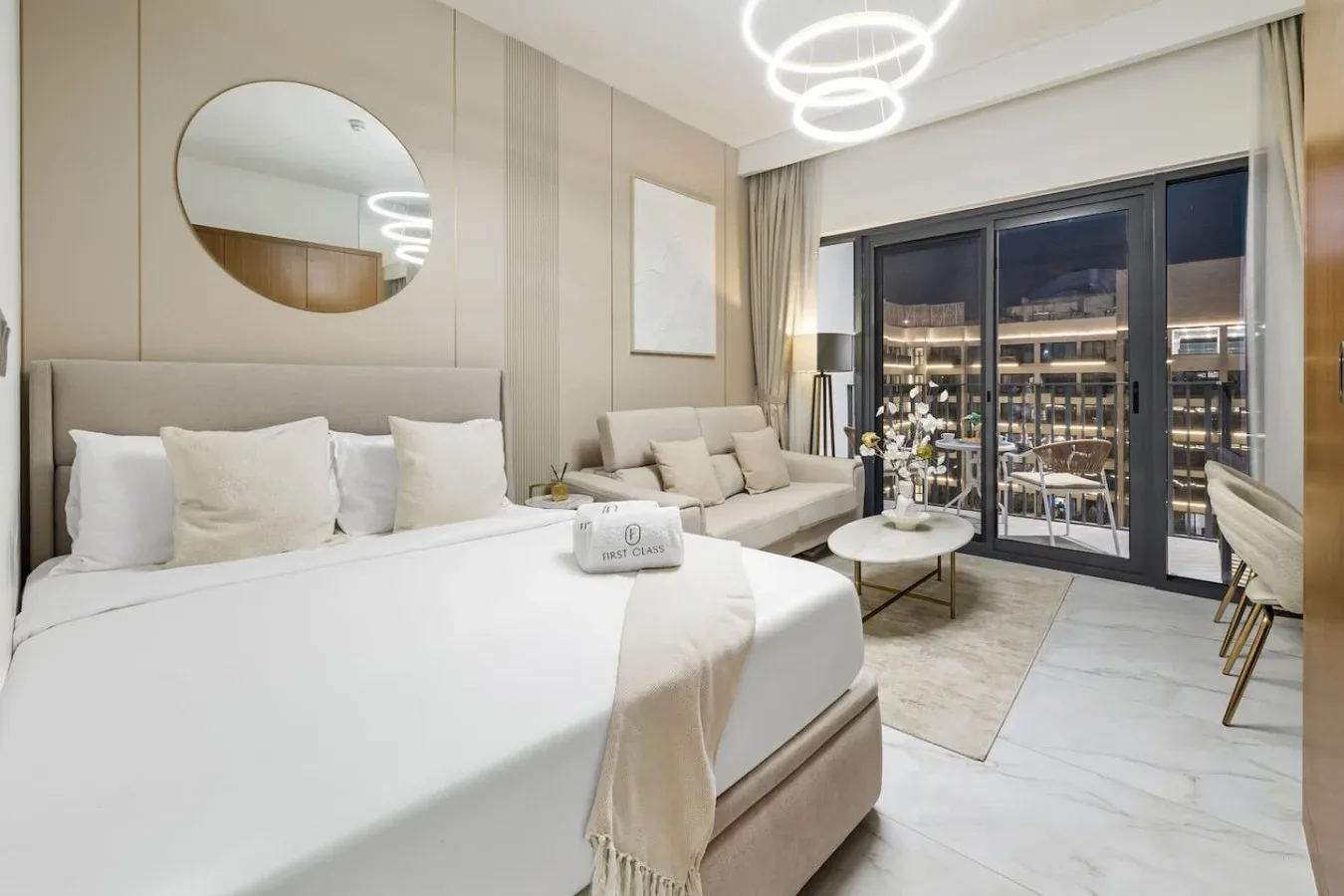 Dormitorio luminoso con una cama grande, zona de estar y puertas de cristal.