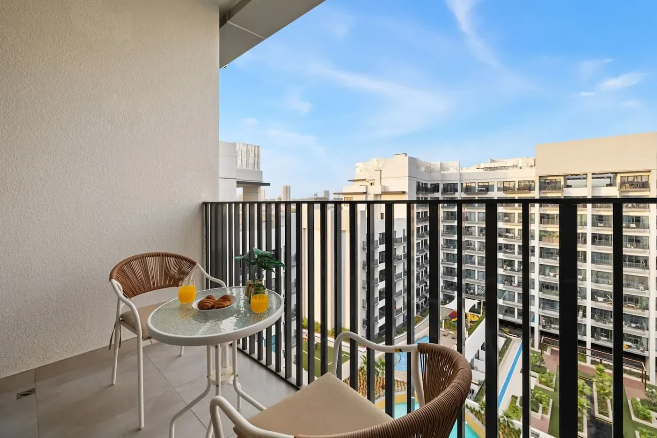 Una zona de estar en un balcón da a edificios de apartamentos bajo un cielo azul.