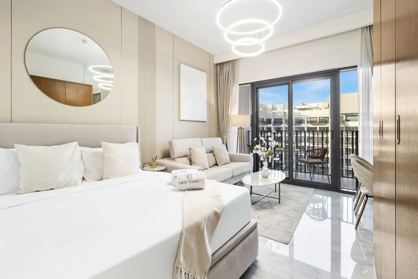 Un dormitorio luminoso con una cama grande, una zona de estar y puertas de vidrio que dan a un balcón.