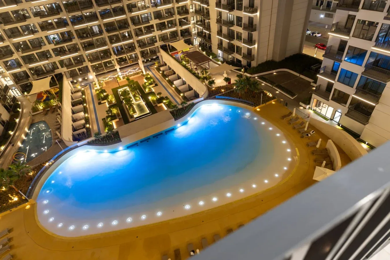 Una gran piscina iluminada se encuentra dentro de un complejo de varios pisos por la noche.