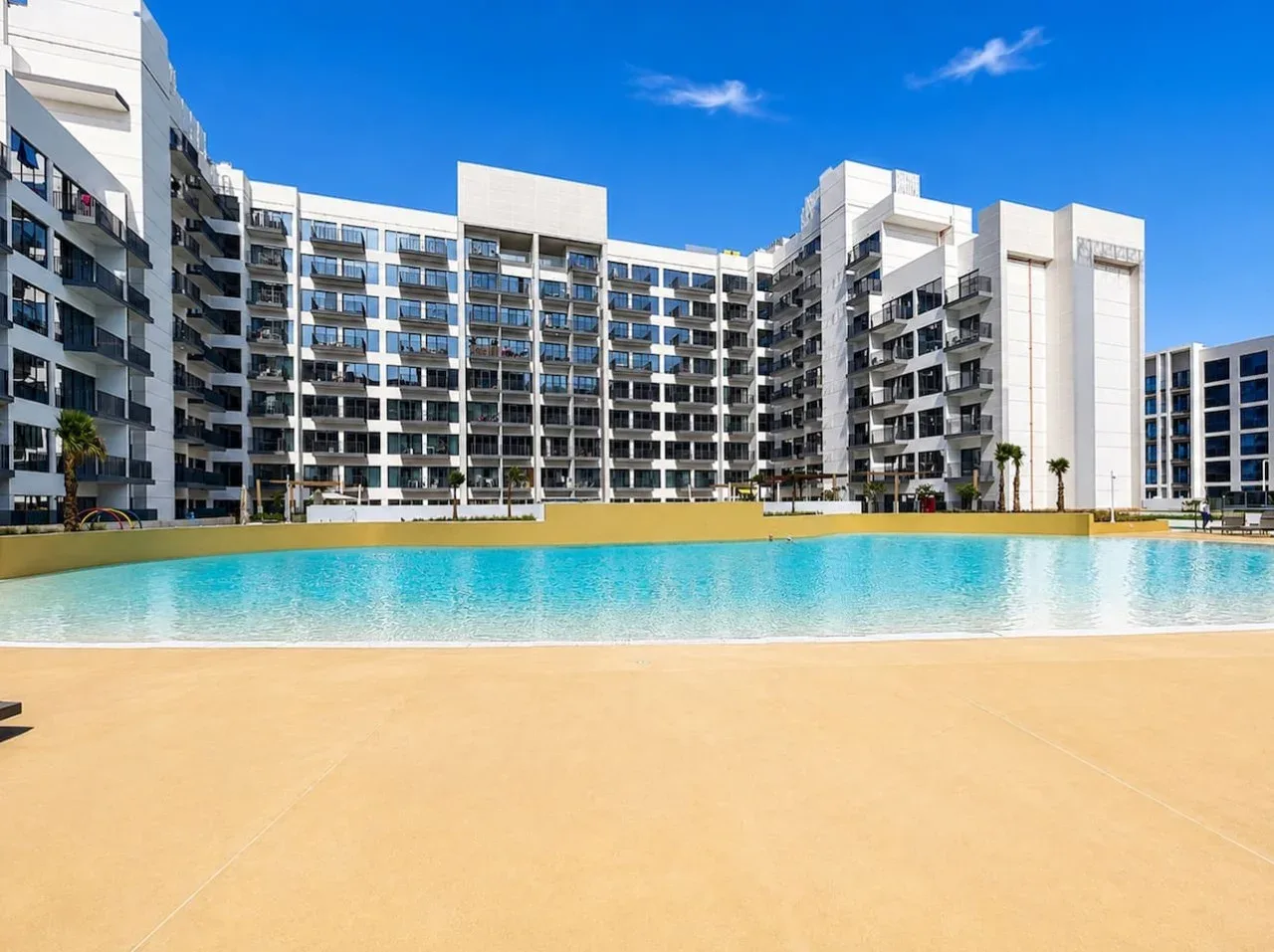 Una gran piscina al aire libre está frente a un edificio de varios pisos.