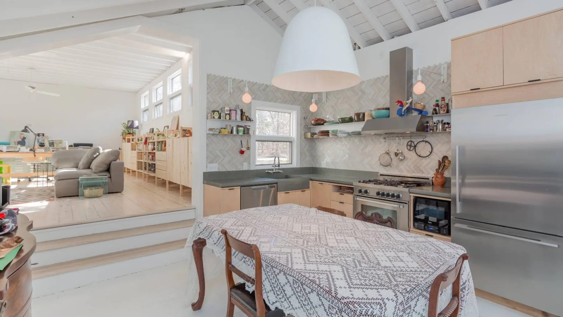 Una cocina abierta con comedor, mantel estampado y electrodomésticos de acero inoxidable.