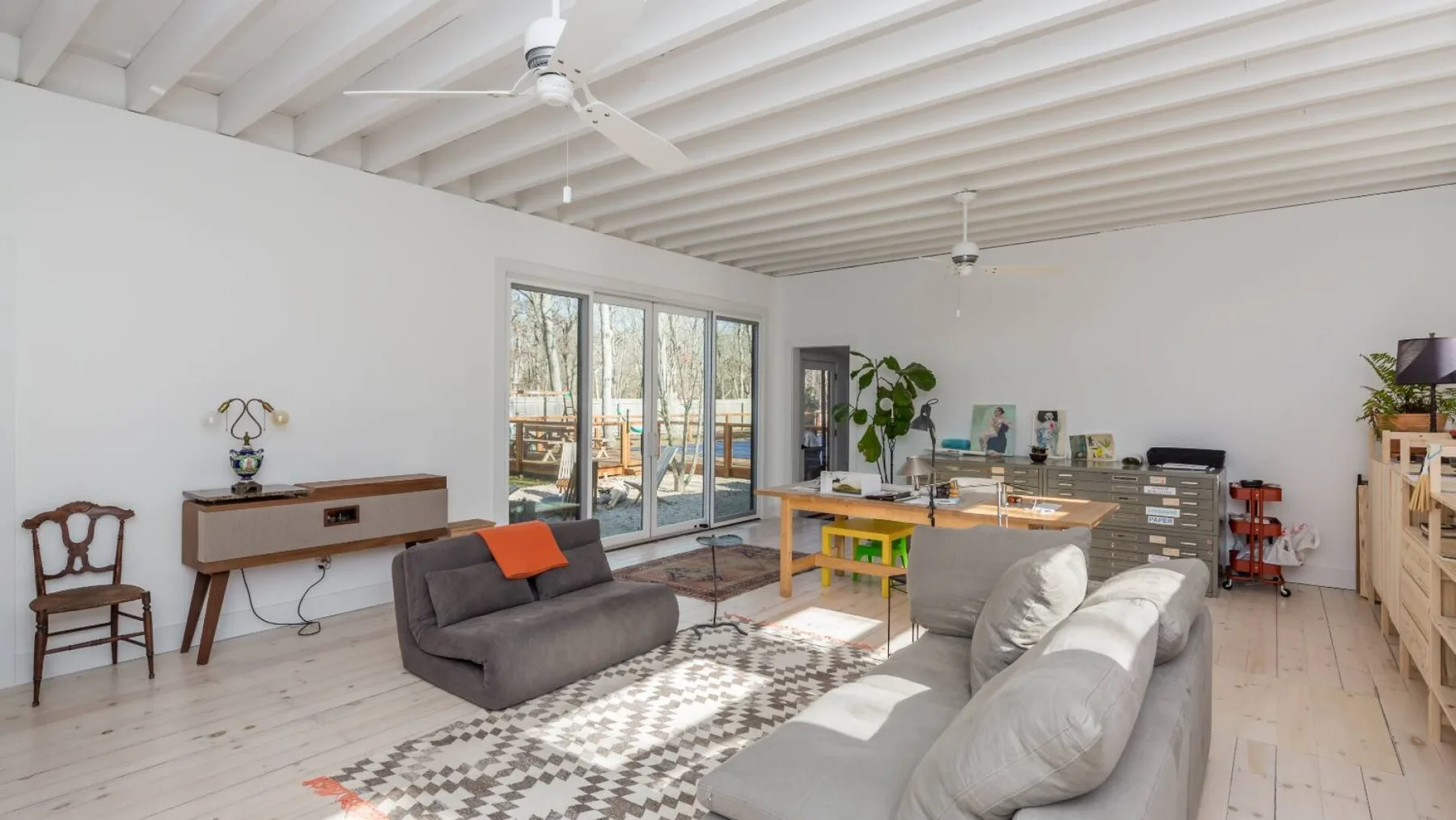 Una sala luminosa con asientos, una mesa de comedor y puertas de vidrio que dan a un patio.