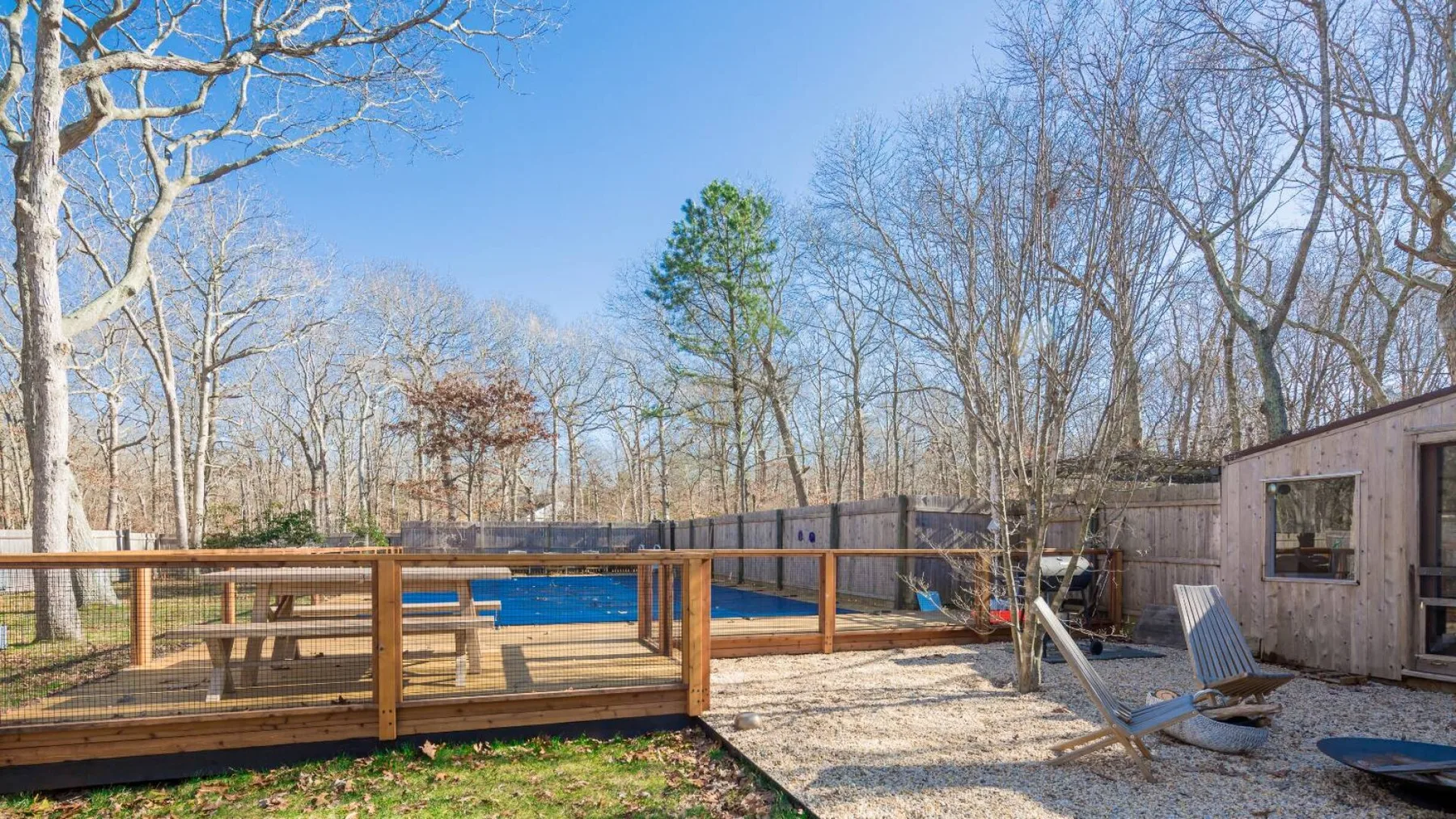 Una piscina al aire libre junto a una terraza de madera y un patio pequeño.