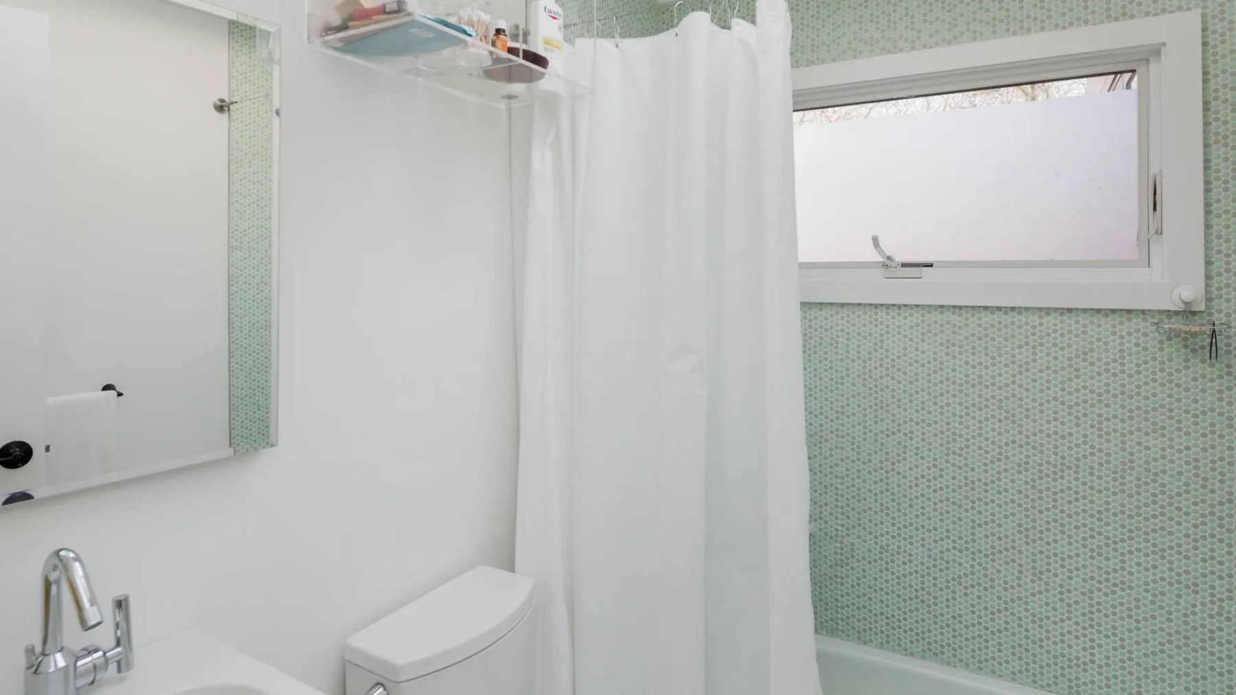 Un baño con cortina de ducha, inodoro y ventana translúcida.
