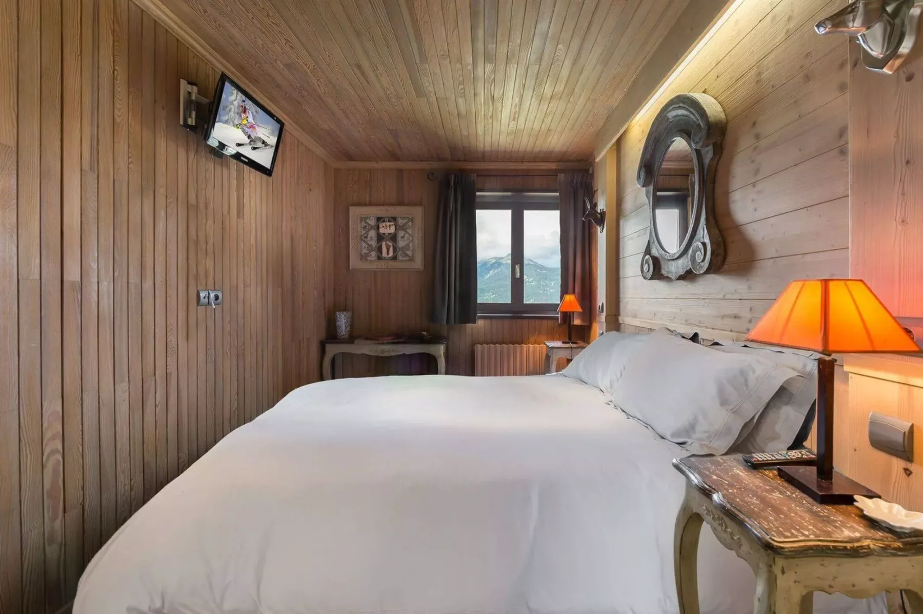 A wood-paneled bedroom with a bed and a window overlooking the mountains.