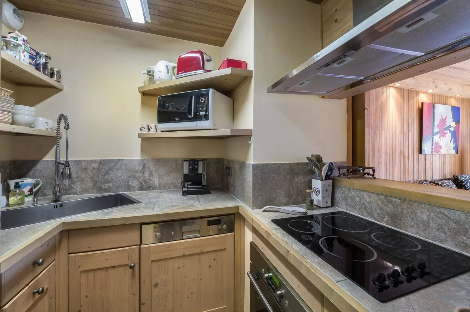 A compact kitchen with wood cabinetry, a sink, and a cooktop.