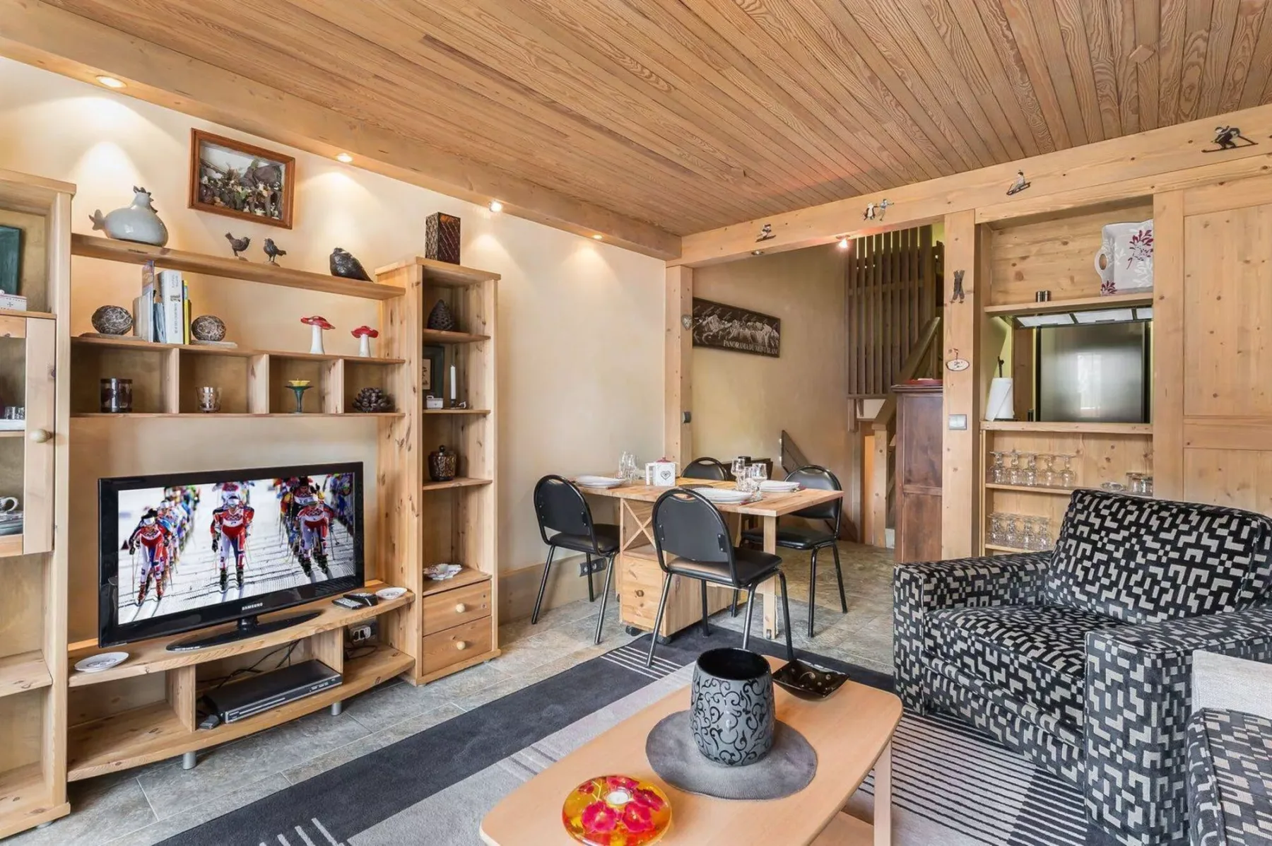 A wood-paneled living room with shelving, a television, and patterned seating.