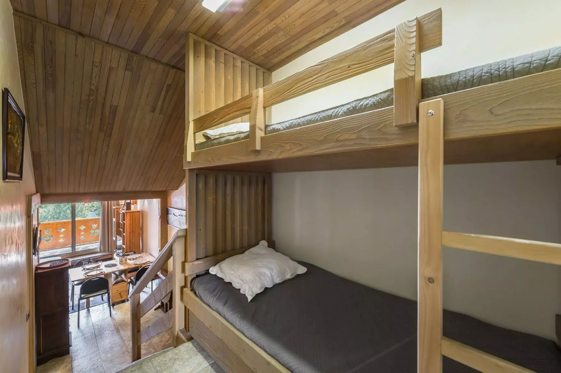 A wooden bunk bed with dark bedding sits in a compact sleeping area.