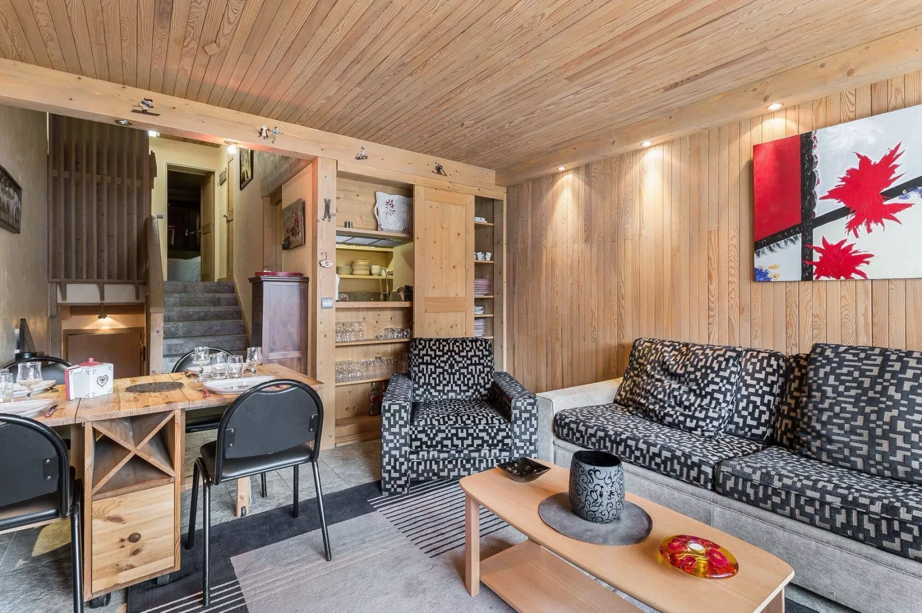 A wood-paneled living room with patterned seating and a low coffee table.