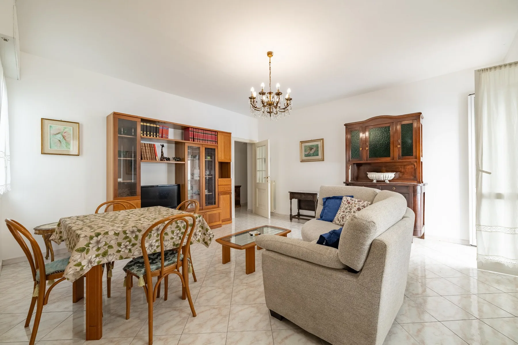 A bright living and dining room with a bookcase, dining table, and seating.