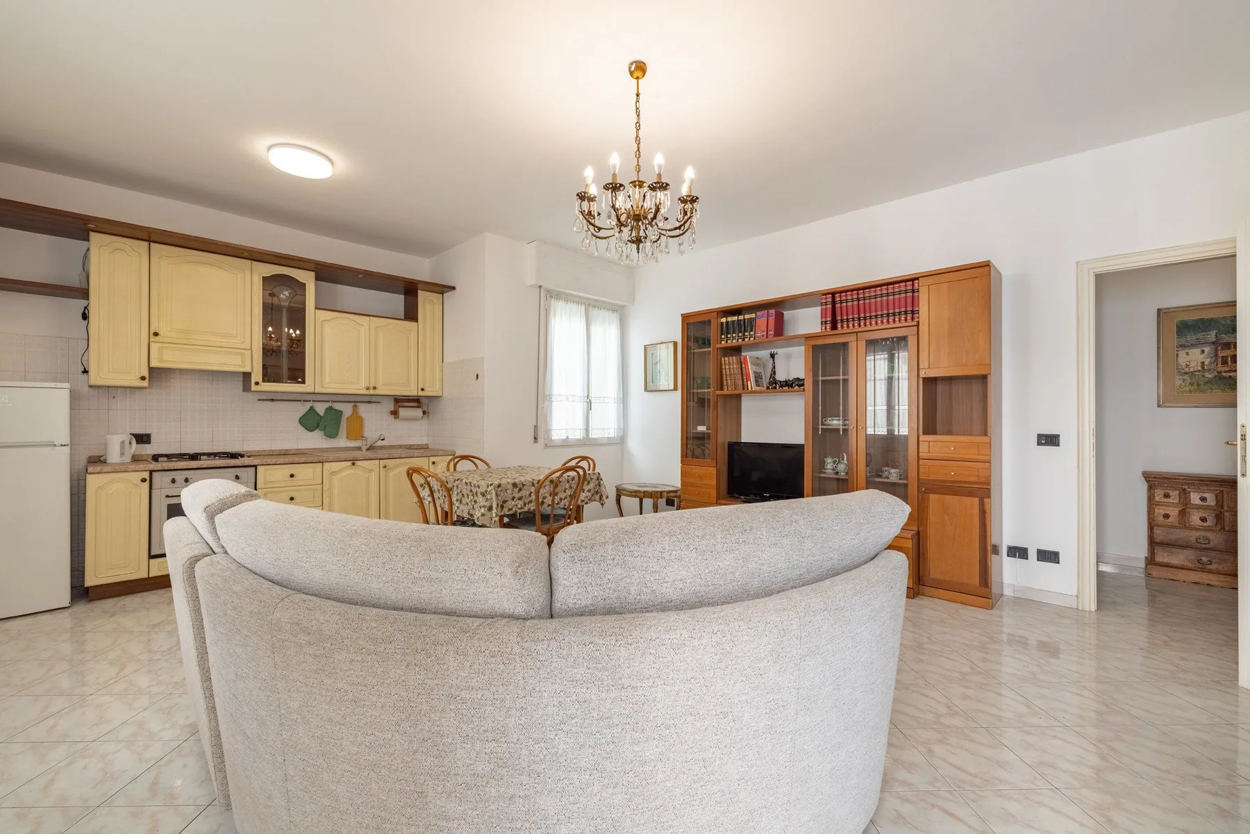 A living room with a curved seating area, wooden cabinets, and a dining table.