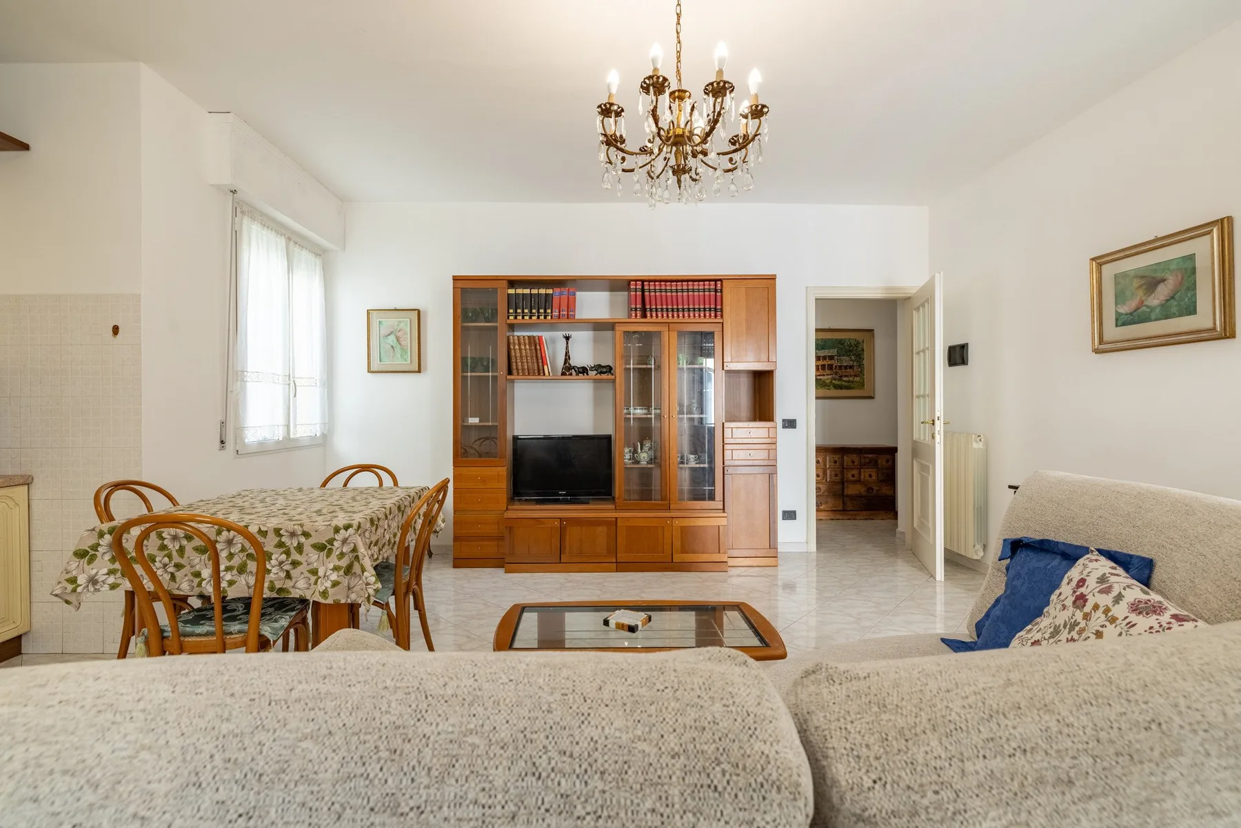 A living room with seating, a television cabinet, and a dining area.