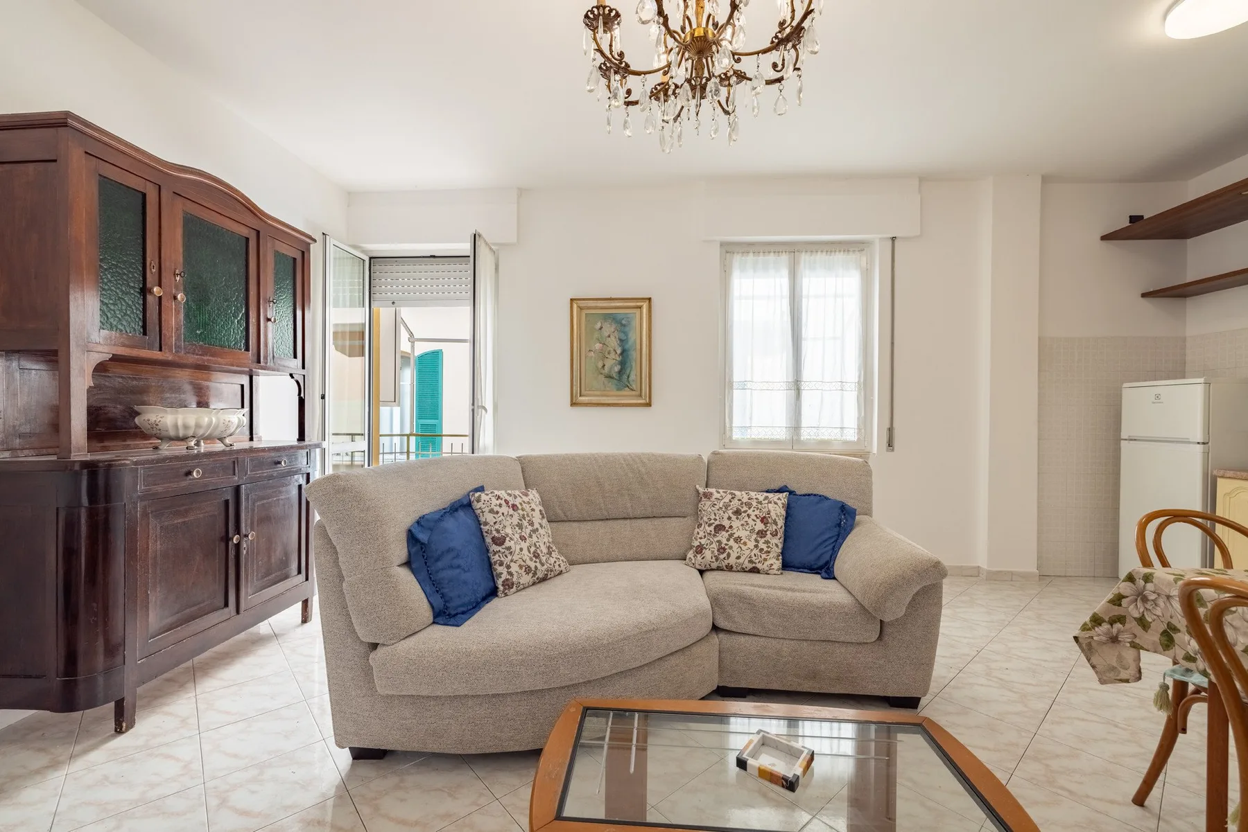A bright living room with a beige sectional sofa and a glass coffee table.