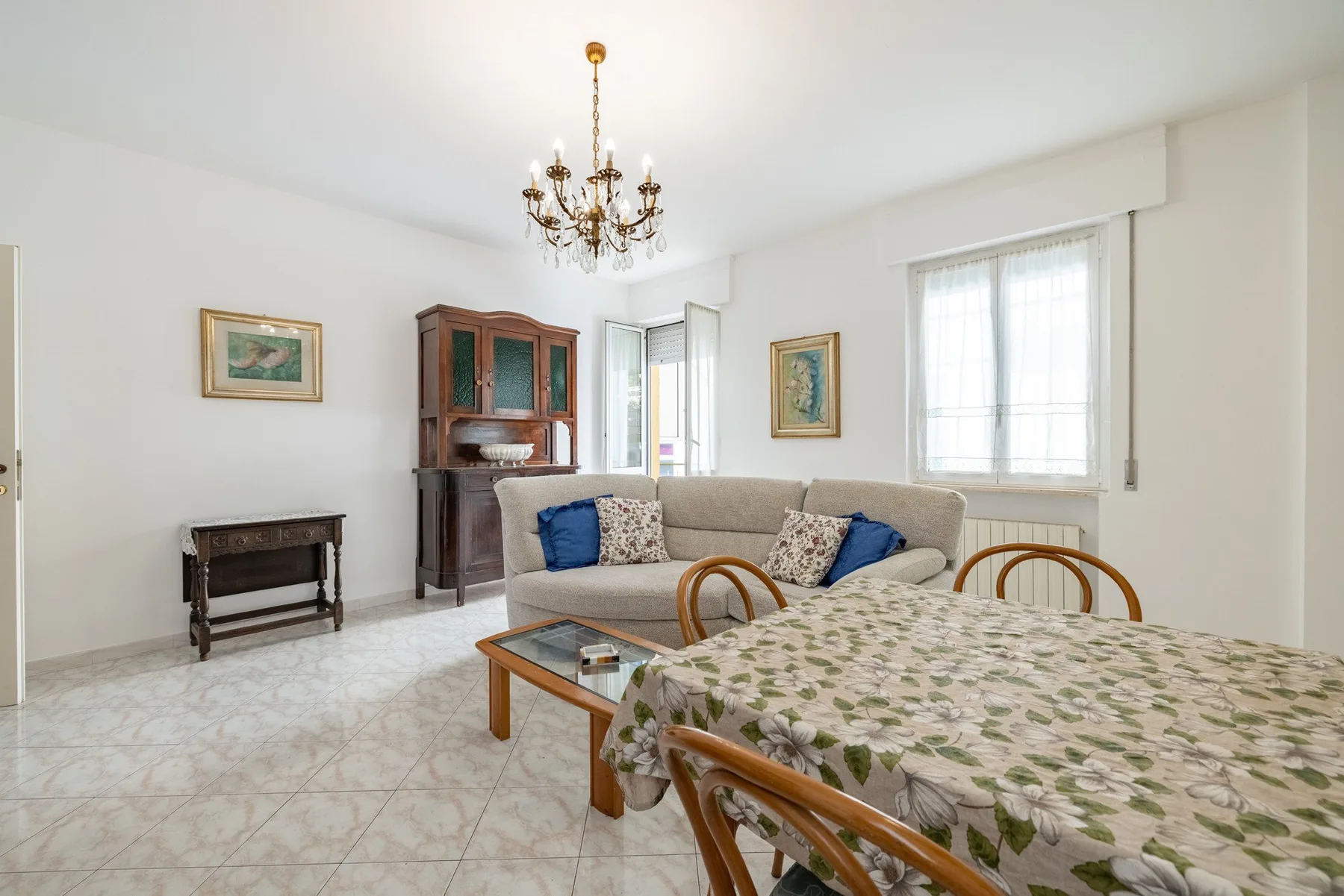 A bright living and dining room with a seating area and a table by the window.